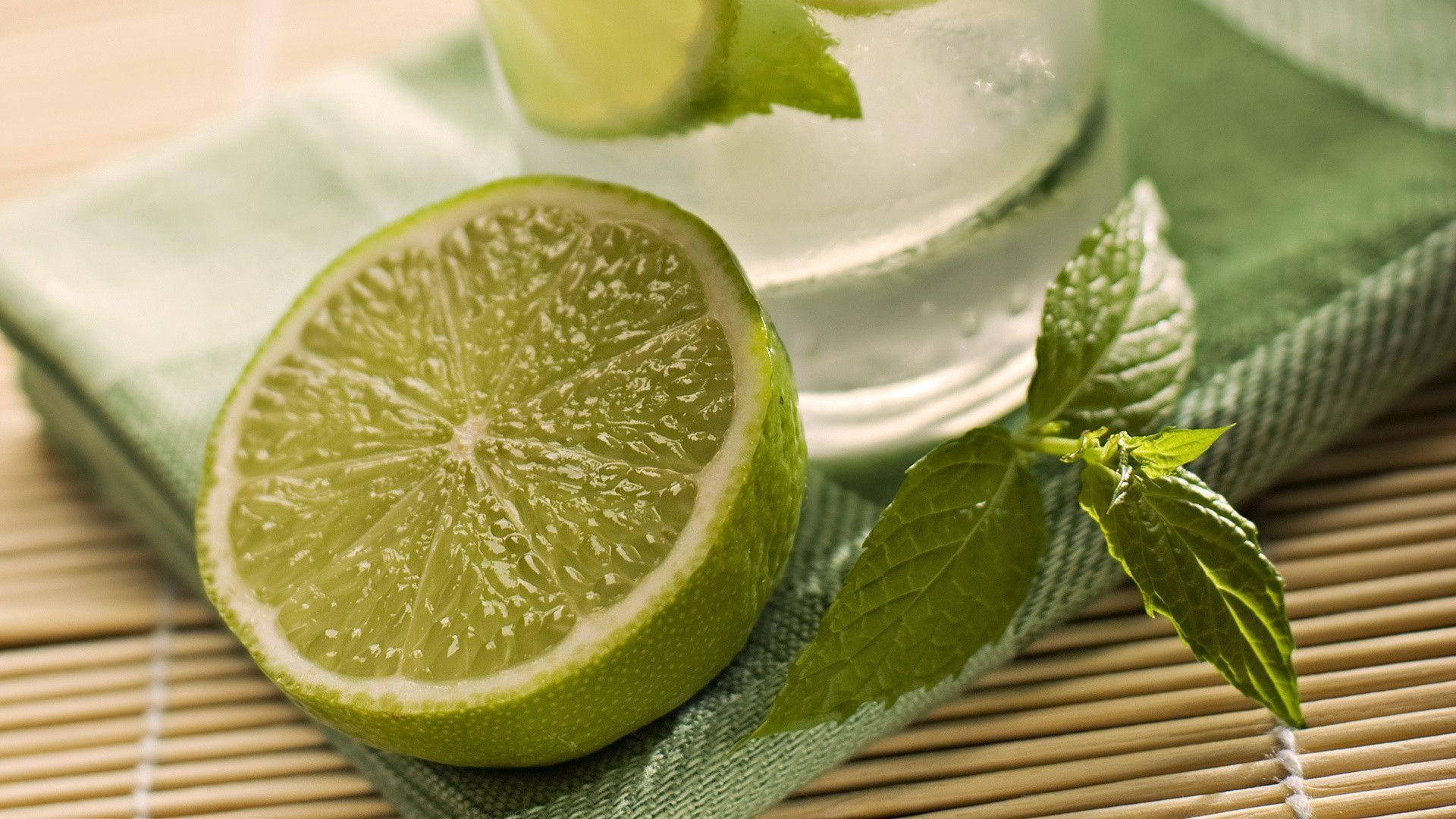 Drink 桌布 壁紙 — 一片鮮豔的萊姆片放在一杯以薄荷裝飾的清涼飲品旁邊，置於竹子上方的綠色布料上。