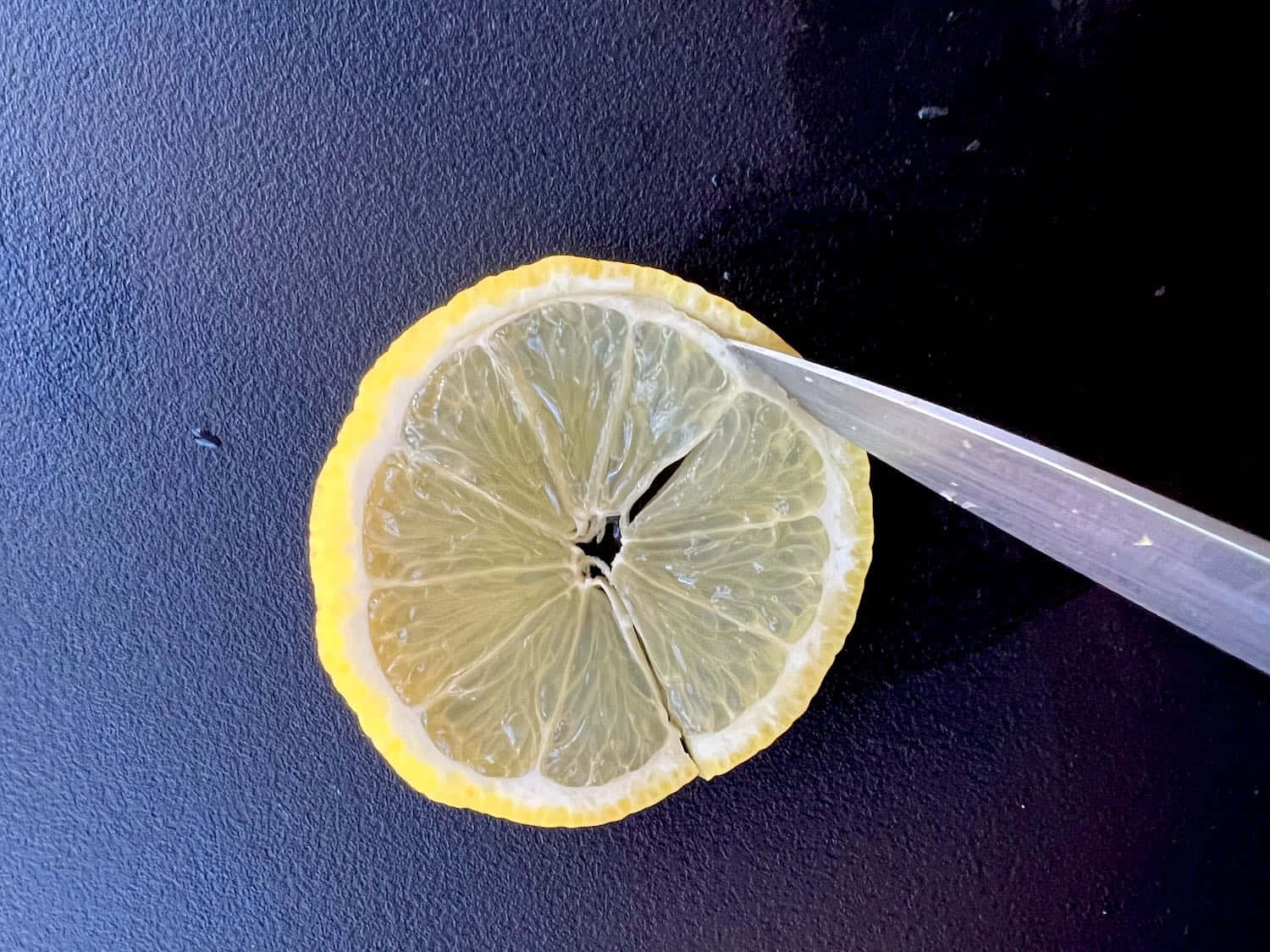 Lime 桌布 壁紙 — 一片鮮黃色的檸檬片放在深色紋理表面上，一把刀正切開其多汁的果瓣。