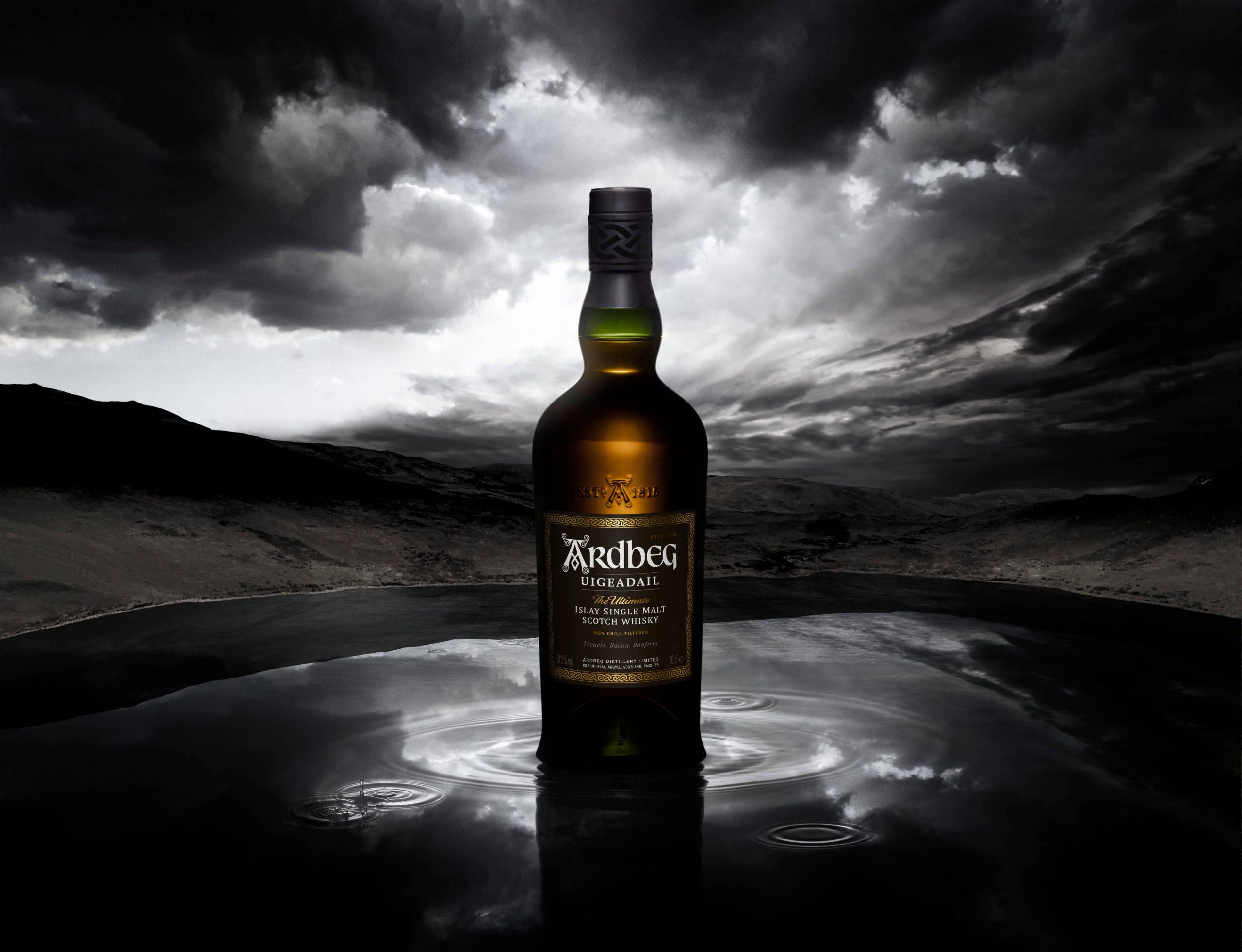 drinks 桌布 壁紙 — 一瓶 Ardbeg Uigeadail 威士忌立在黑暗的反射水池中，上方是風暴天空，帶有戲劇性的雲層。