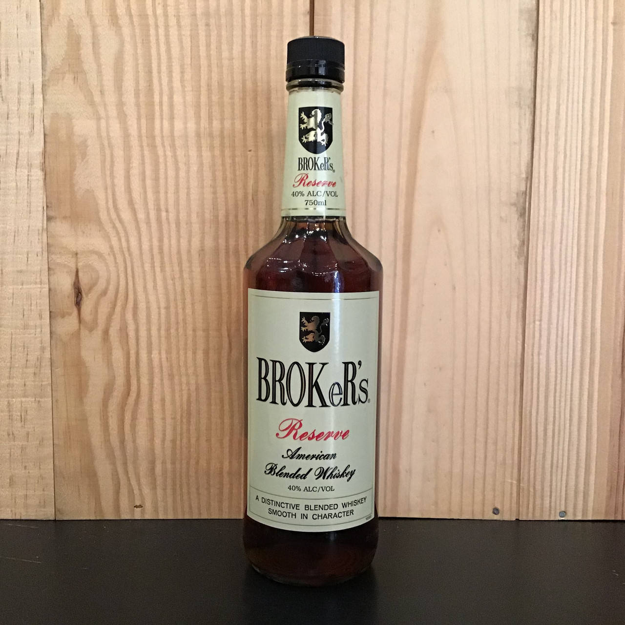 bottle 桌布 壁紙 — 一瓶 Broke's Reserve American Blended Whiskey 在深色表面上，以淺色木紋面板背景為中心擺放。