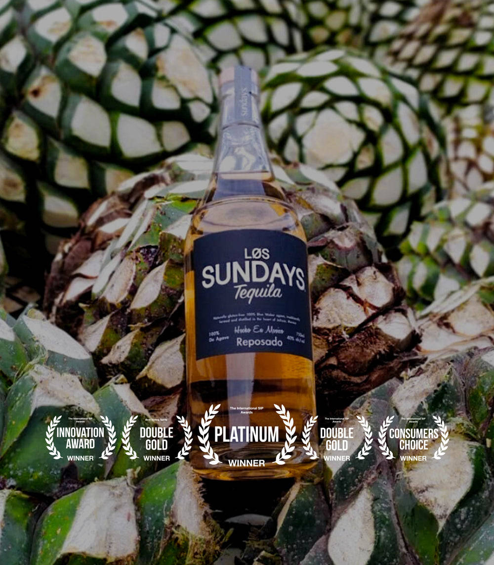 Cactus 桌布 壁紙 — 一瓶 Los Sundays Reposado 龍舌蘭酒放在綠色龍舌蘭植物之間，下方展示獎項桂冠。