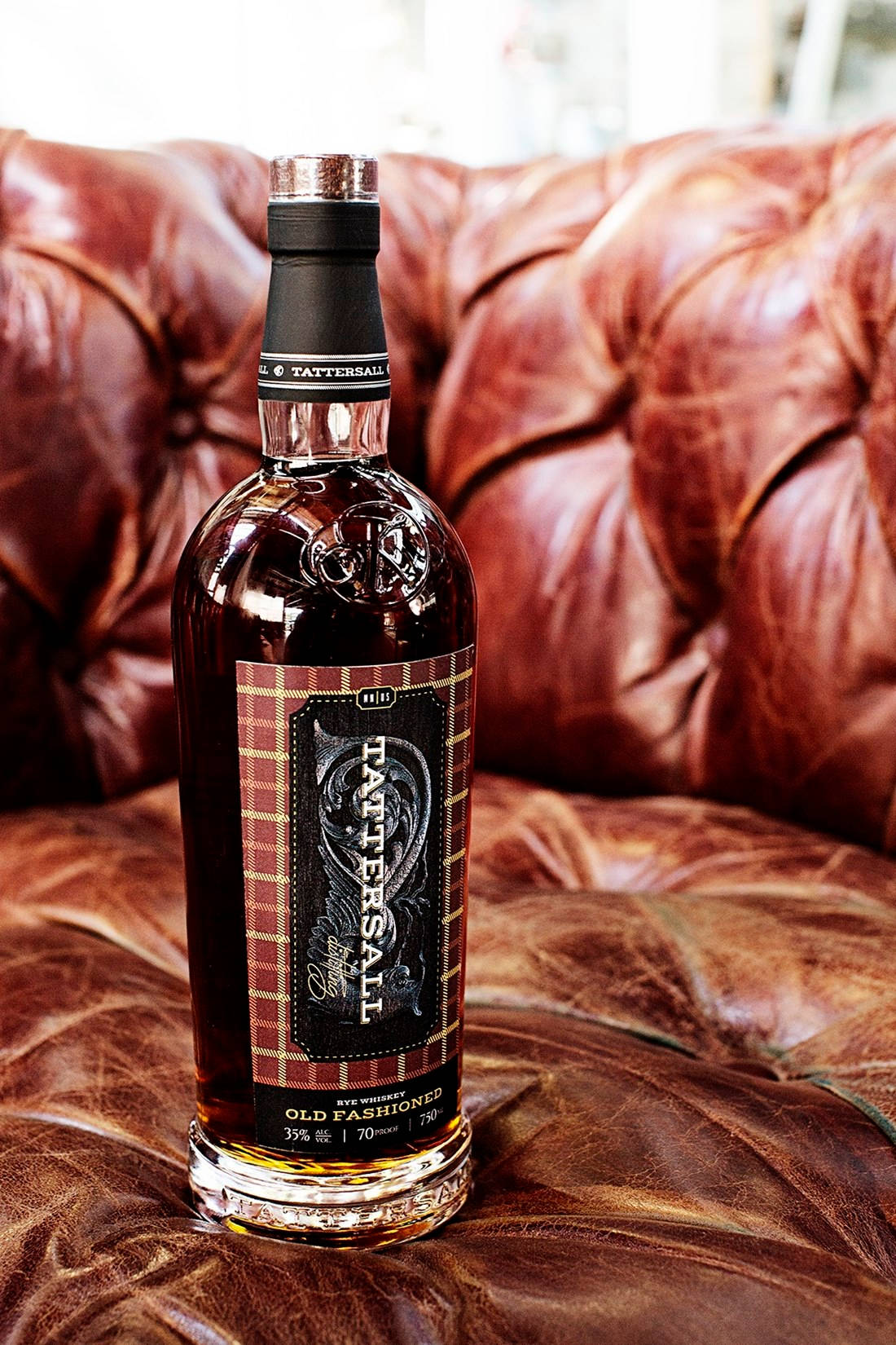 飲料 桌布 壁紙 — 一瓶 Tattersall Old Fashioned 威士忌優雅地放置在濃郁的棕色簇絨皮革沙發上。