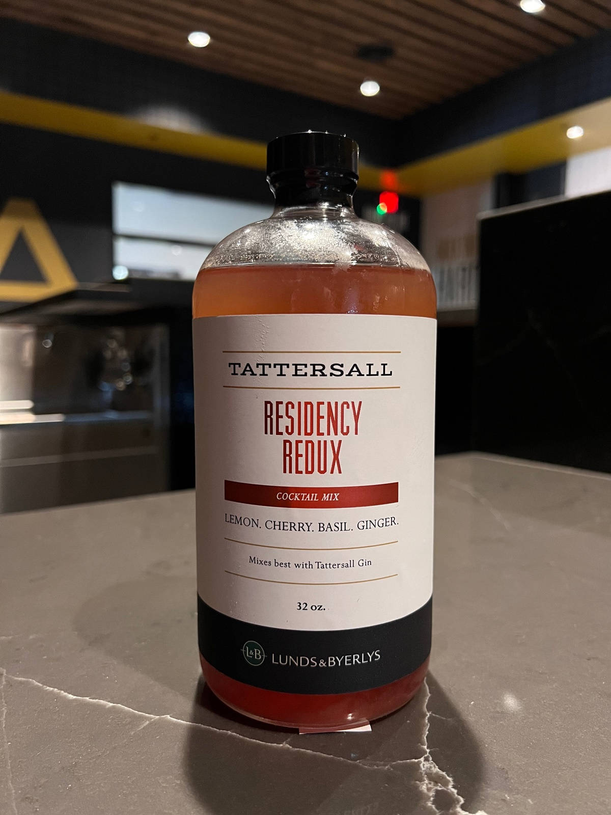 Drink 桌布 壁紙 — 一瓶 Tattersall Residency Redux 雞尾酒調配液放在現代酒吧環境的灰色大理石檯面上。