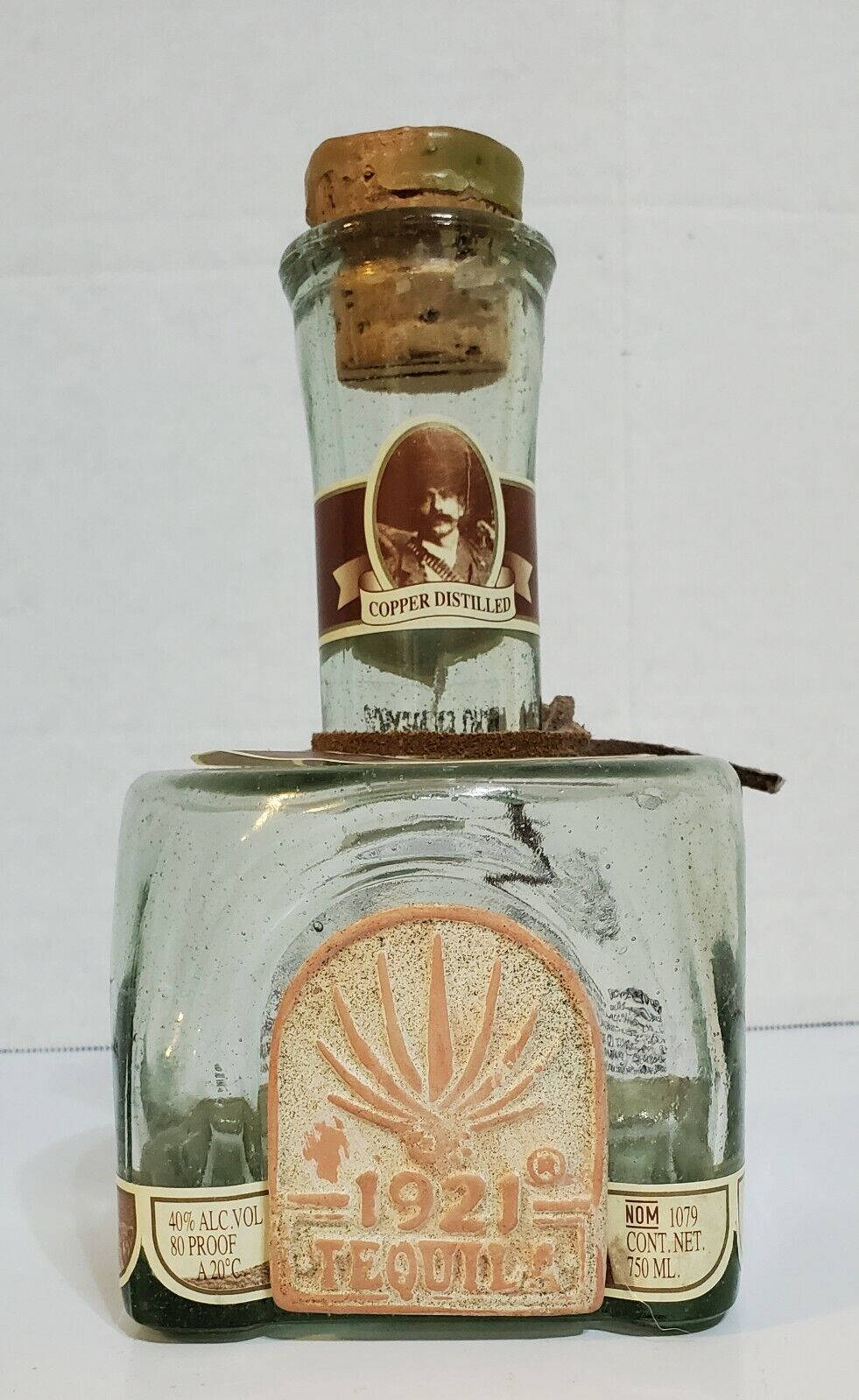 桌布 壁紙 — 一瓶1921年復古龍舌蘭酒，帶有銅蒸餾標籤和軟木塞，直立於純白色背景前。