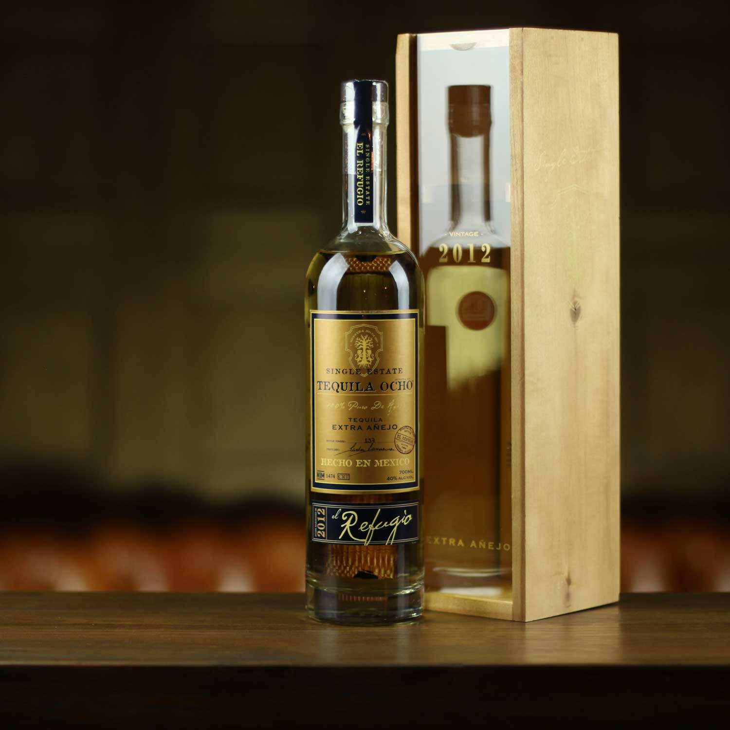bottle 桌布 壁紙 — 一瓶2012年陳年龍舌蘭酒優雅地放在其木製禮盒旁邊，置於深色木質表面上。
