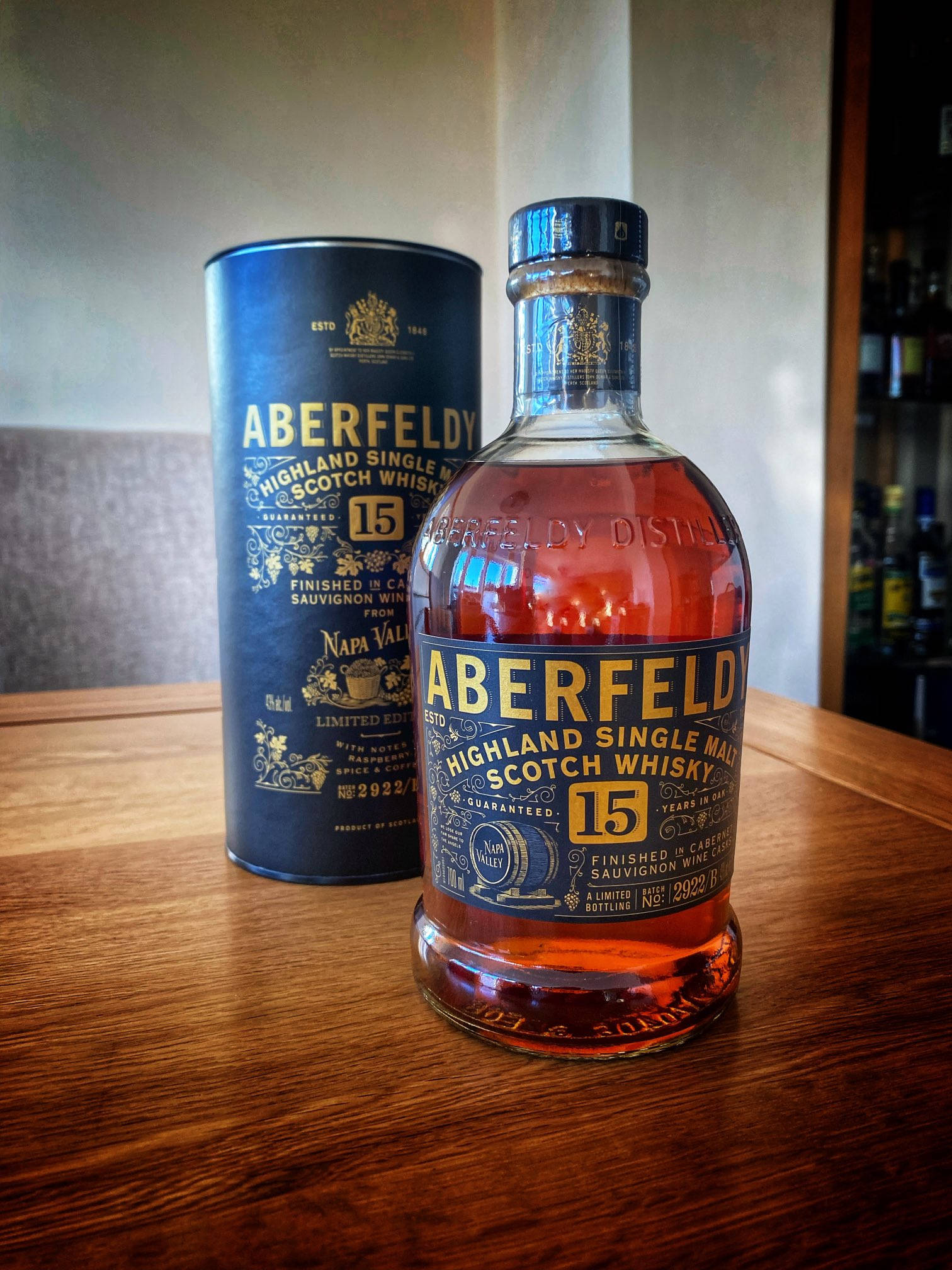 Drink 桌布 壁紙 — 一瓶Aberfeldy 15年高地單一麥芽蘇格蘭威士忌放在溫暖的木桌上，旁邊是它的藍色圓筒。