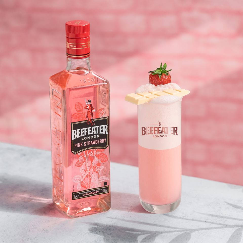 Chocolate 桌布 壁紙 — 一瓶Beefeater Pink Strawberry琴酒放在一杯粉紅色雞尾酒旁邊，雞尾酒上放有白巧克力和草莓，背景是柔和的粉紅色磚牆。