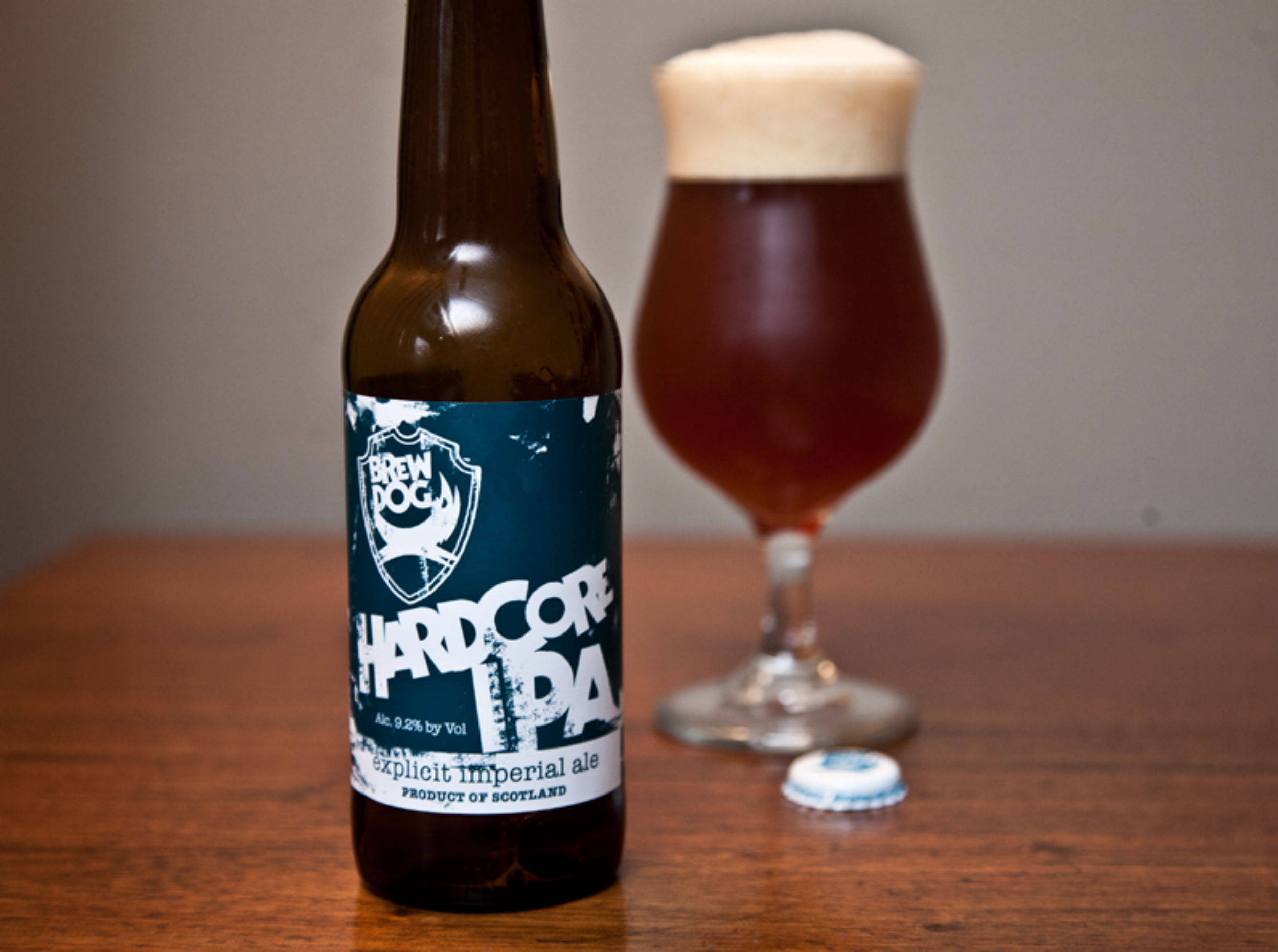 Drink 桌布 壁紙 — 一瓶BrewDog Hardcore IPA棕色啤酒放在木桌上，旁邊有一杯帶有泡沫的琥珀色啤酒。