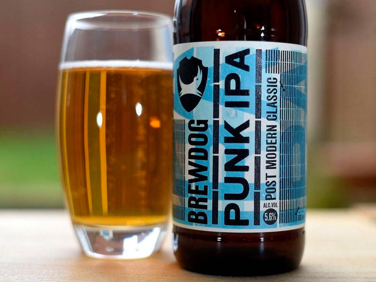 Drink 桌布 壁紙 — 一瓶BrewDog Punk IPA放在木質表面上，旁邊是一個裝滿金黃色啤酒和白色泡沫的玻璃杯。