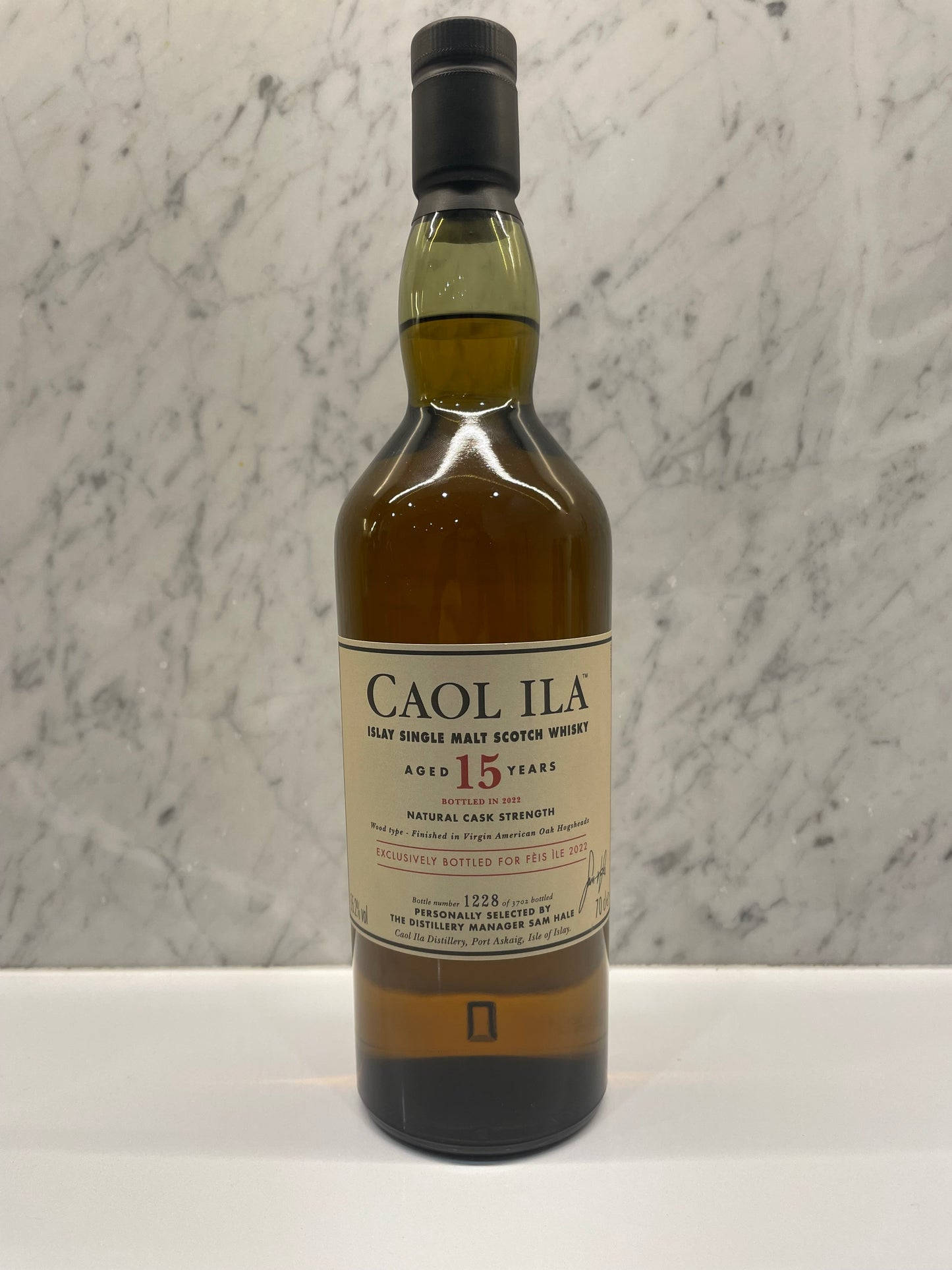 alcohol 桌布 壁紙 — 一瓶Caol Ila 15年單一麥芽蘇格蘭威士忌，置中放在白色表面上，背景是大理石。