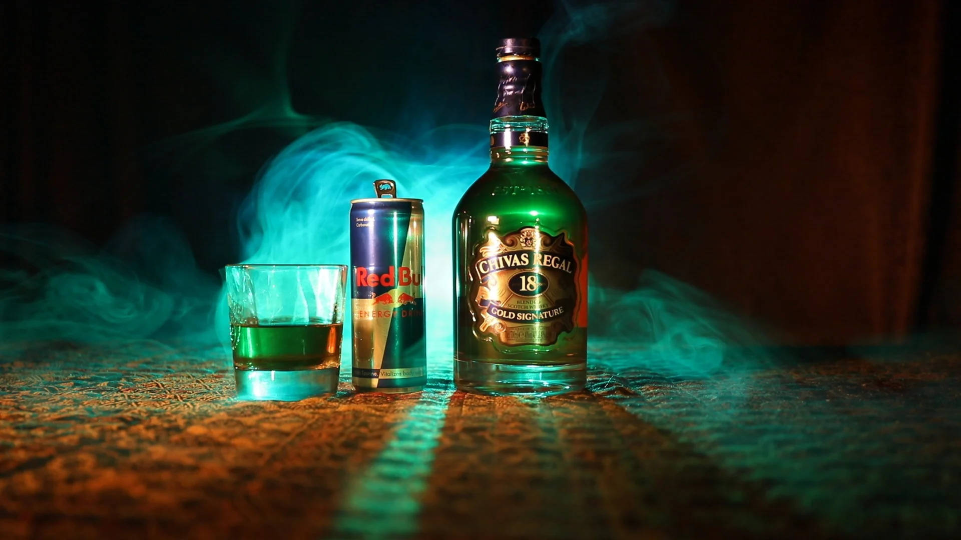 alcohol 桌布 壁紙 — 一瓶Chivas Regal 18和一罐Red Bull在帶有紋理的表面上，在青綠色燈光下發光，煙霧繚繞。
