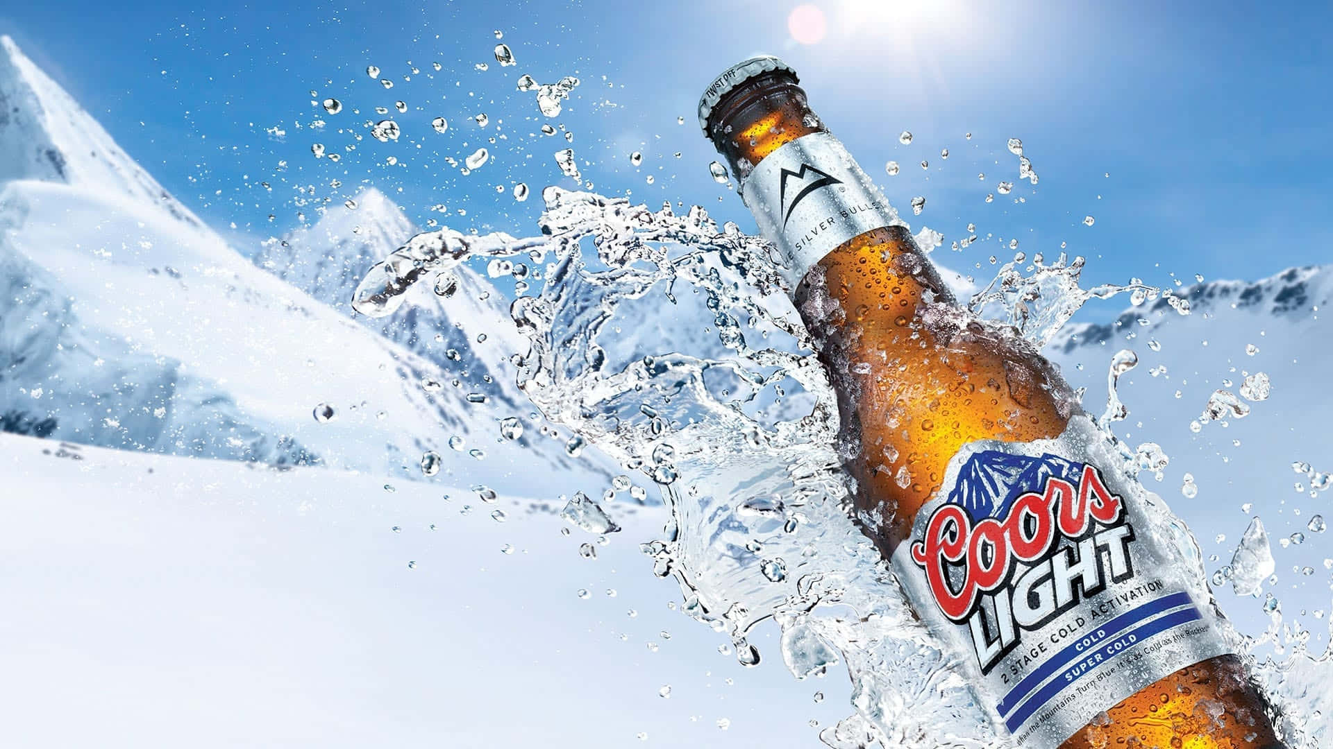 Beer Bottle 桌布 壁紙 — 一瓶Coors Light啤酒穿過冰雪，水花濺向明亮的藍天和雪山。
