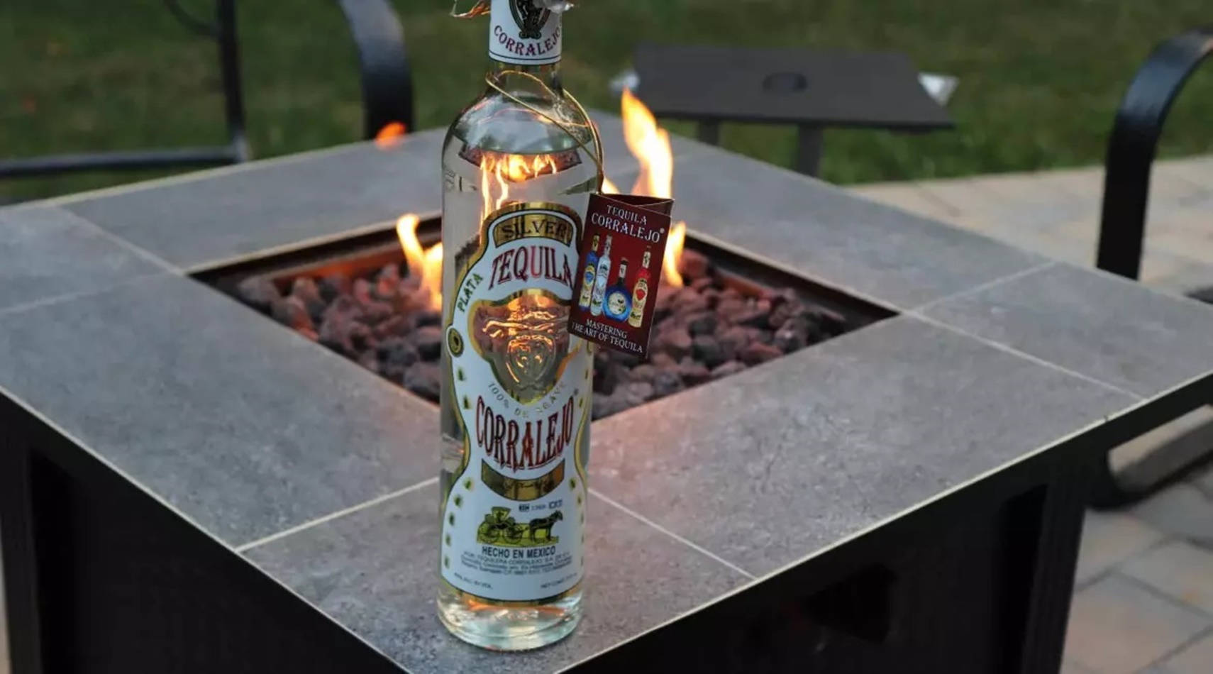 bottle 桌布 壁紙 — 一瓶Corralejo Silver Tequila放在石頭火坑上，黃昏時火焰在後面閃爍。