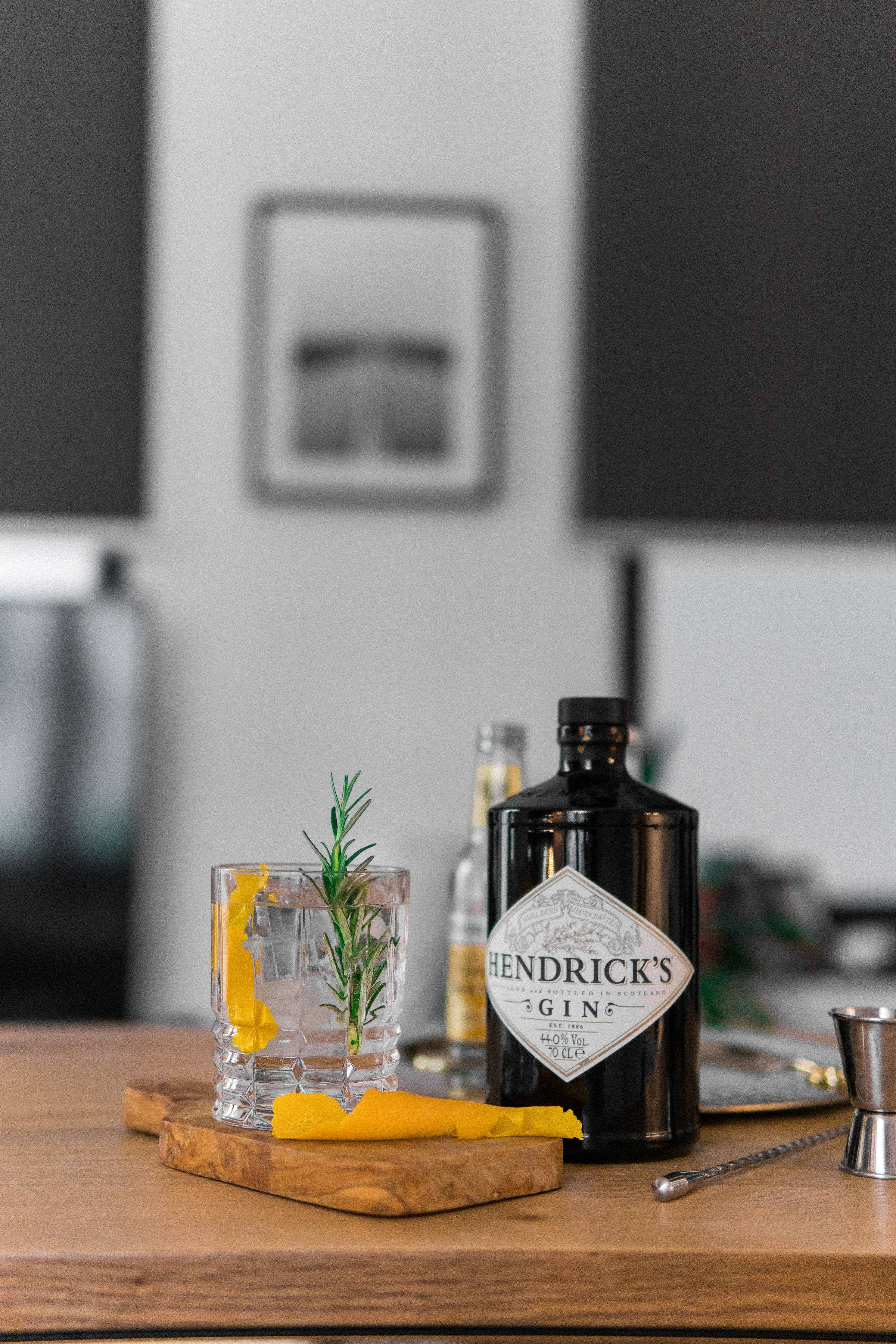 drinks 桌布 壁紙 — 一瓶Hendrick's琴酒和一杯帶有迷迭香和柑橘裝飾的酒杯放在現代廚房的木板上。