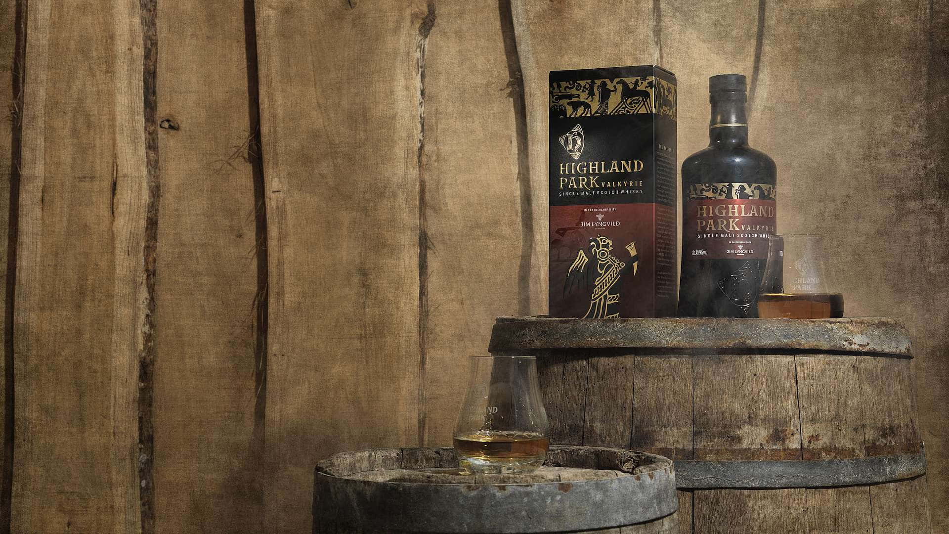 booze 桌布 壁紙 — 一瓶Highland Park Valkyrie威士忌和一個酒杯放在質樸的木桶上，背景是風化的木牆。