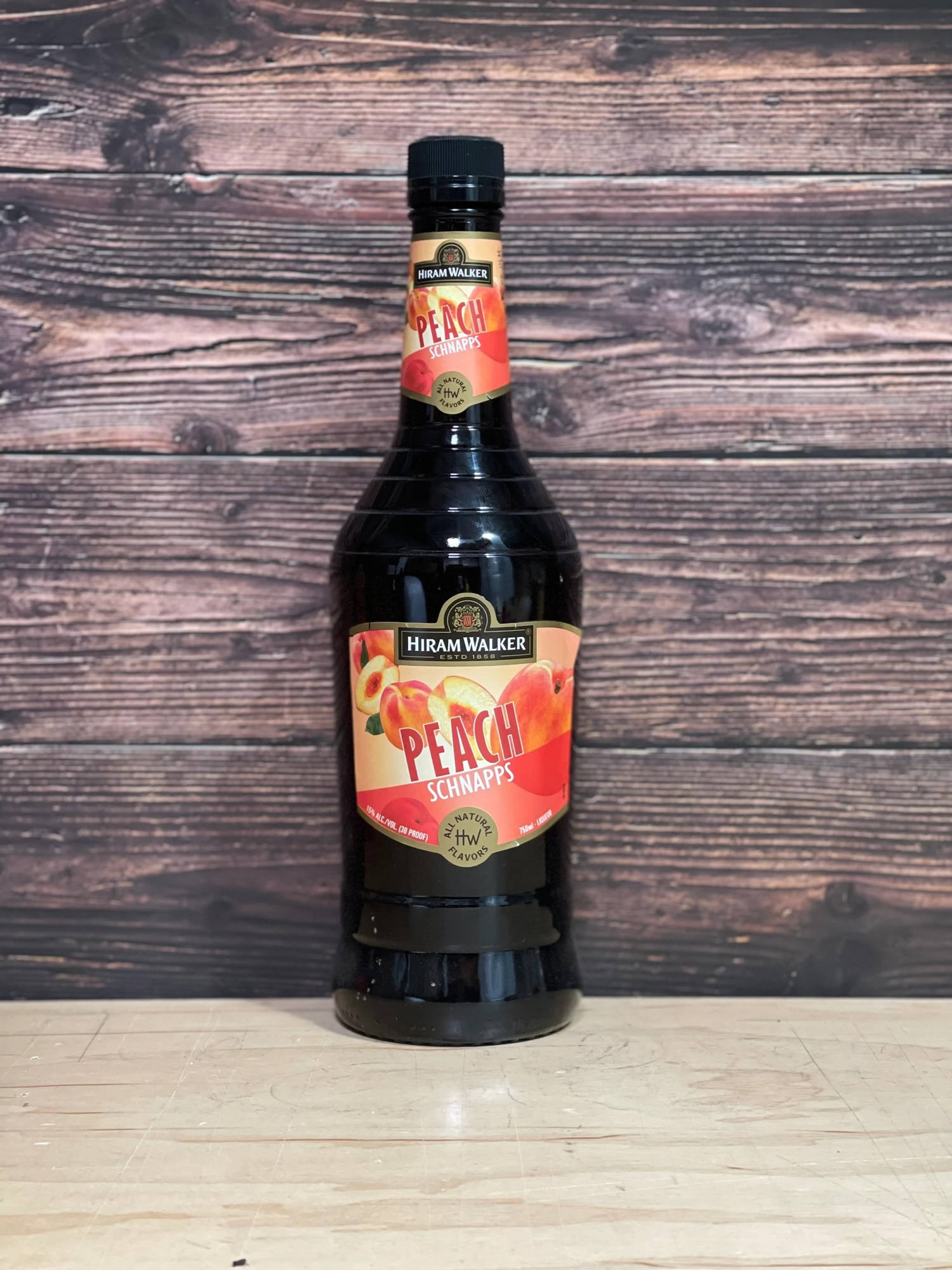 alcohol 桌布 壁紙 — 一瓶Hiram Walker Peach Schnapps放在淺色木質表面上，背景是深色質樸的木質背景。