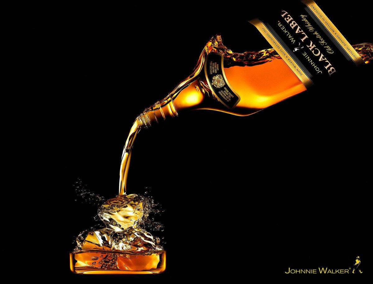alcohol 桌布 壁紙 — 一瓶Johnnie Walker Black Label威士忌在純黑背景下將金色液體倒在冰塊上。