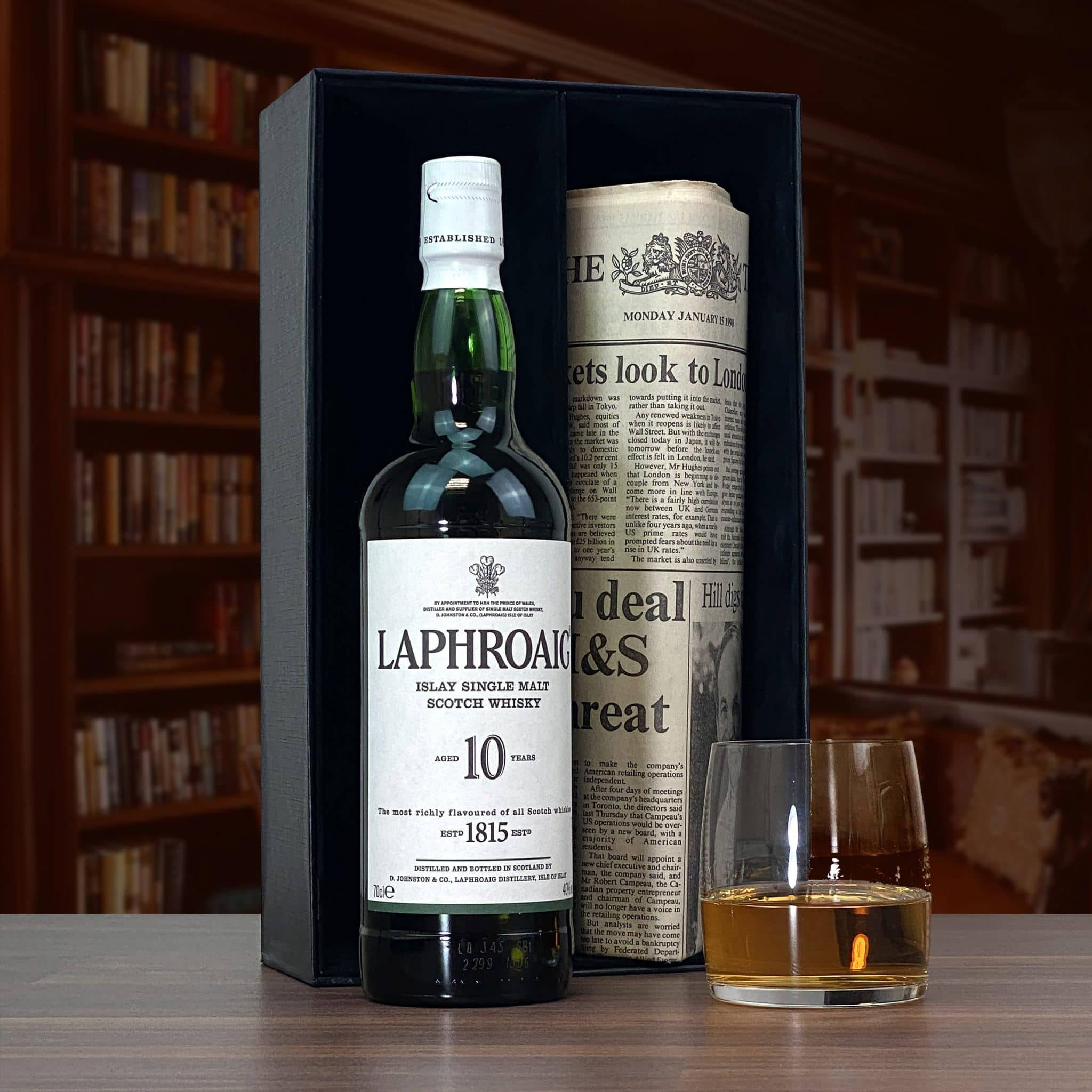 手機 桌布 壁紙 — 一瓶Laphroaig 10年蘇格蘭威士忌放在深色木質圖書館環境中，旁邊有一杯琥珀色液體。