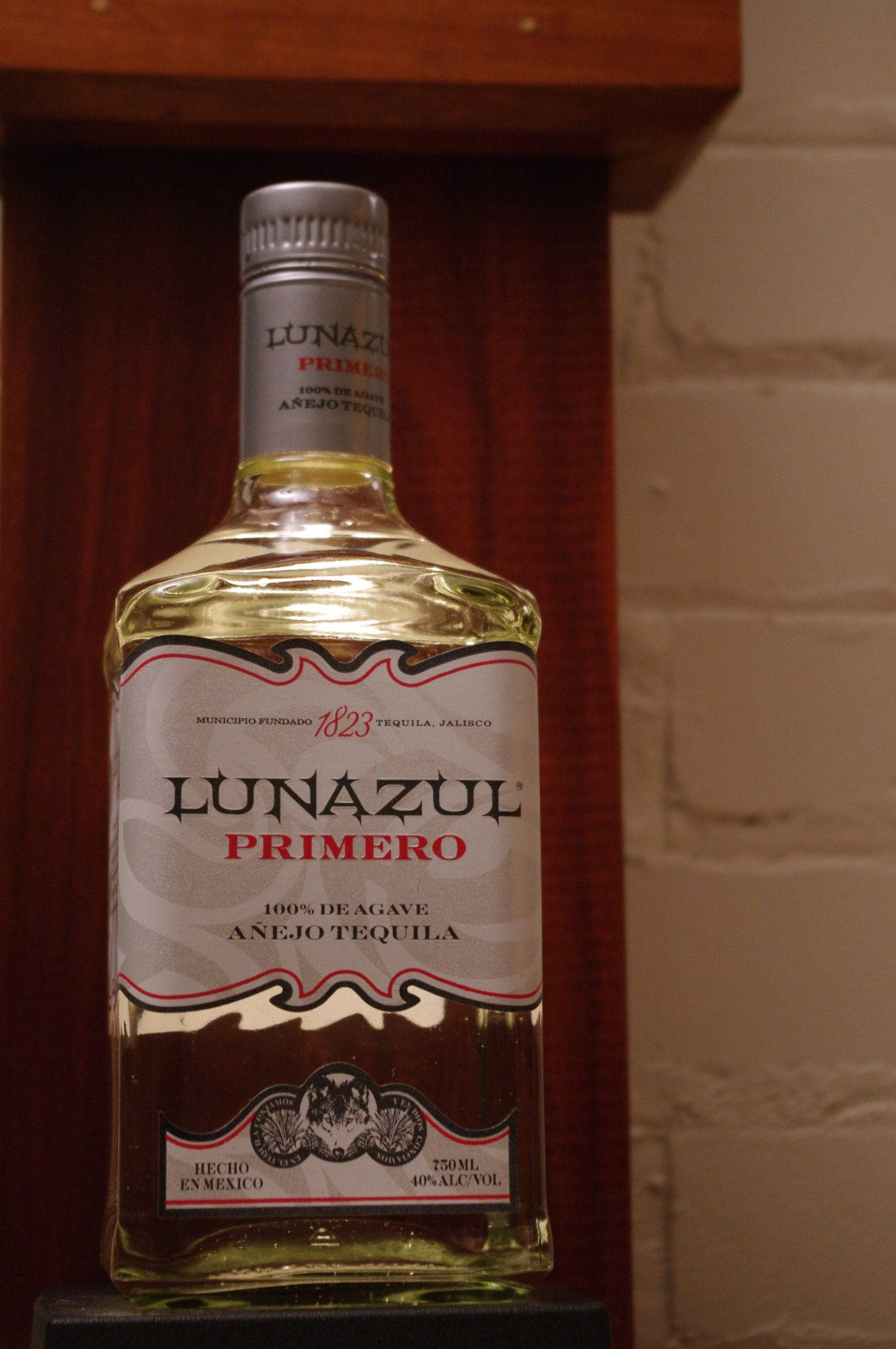 alcohol 桌布 壁紙 — 一瓶Lunazul Primero Añejo龍舌蘭酒放在一個磚牆和木框的架子上。