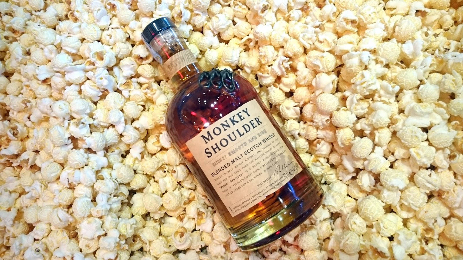 飲料 桌布 壁紙 — 一瓶Monkey Shoulder威士忌放在鬆軟的白色爆米花上。