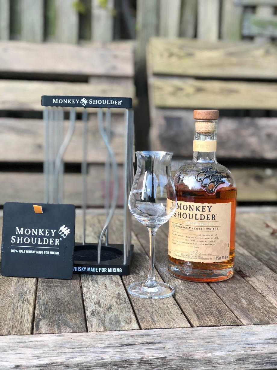 Drink 桌布 壁紙 — 一瓶Monkey Shoulder威士忌和品酒杯放在戶外風化的木桌上，背景是質樸的籬笆。