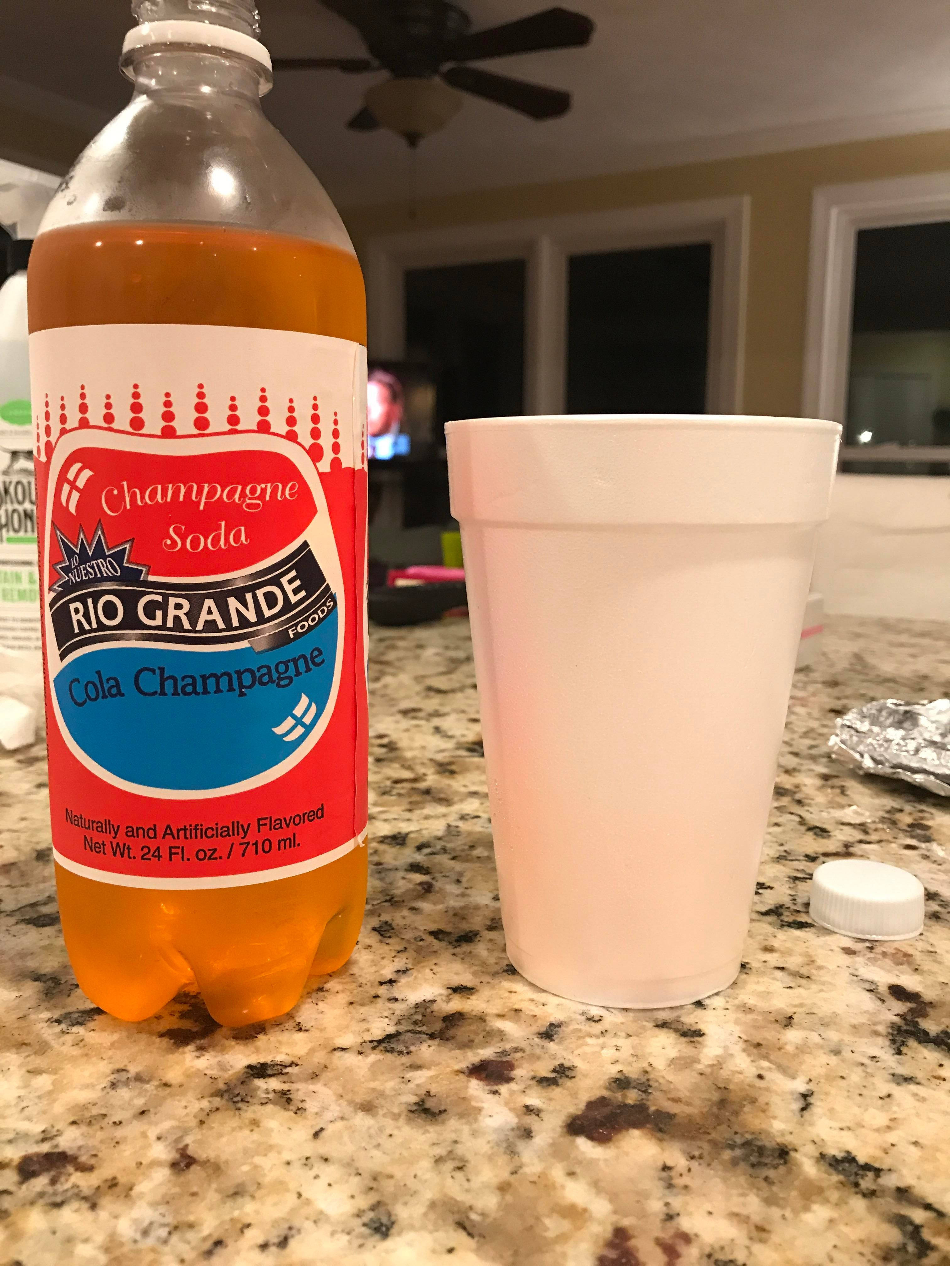 Drink 桌布 壁紙 — 一瓶Rio Grande Cola Champagne汽水放在一個有斑點的廚房檯面上，旁邊有一個白色發泡膠杯。
