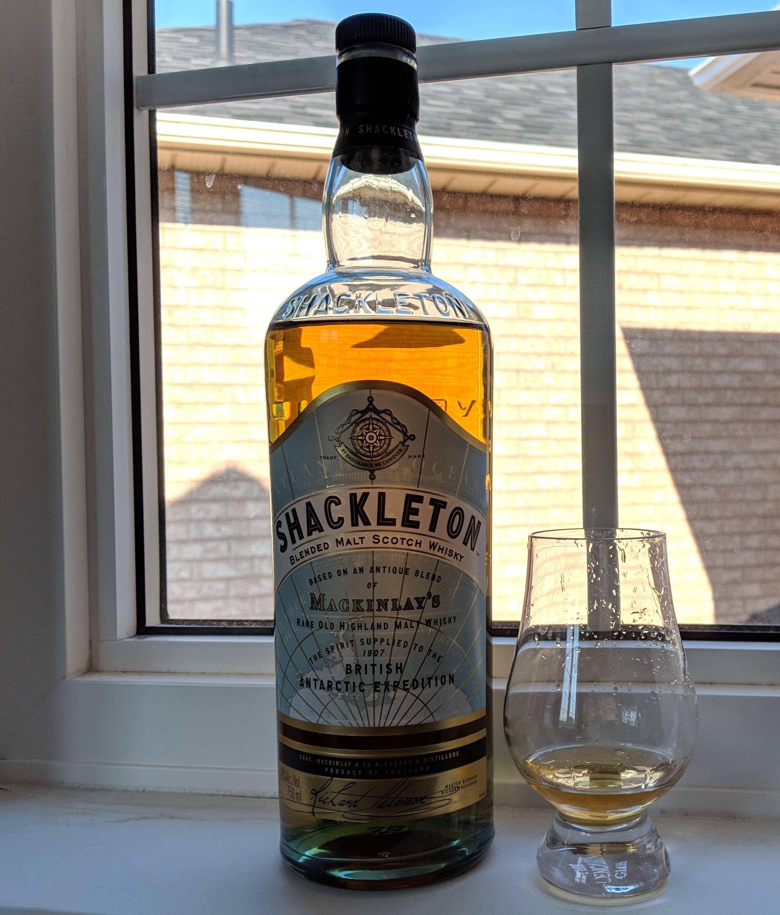 Drink 桌布 壁紙 — 一瓶Shackleton威士忌和一個品酒杯放在灑滿陽光的窗台上。