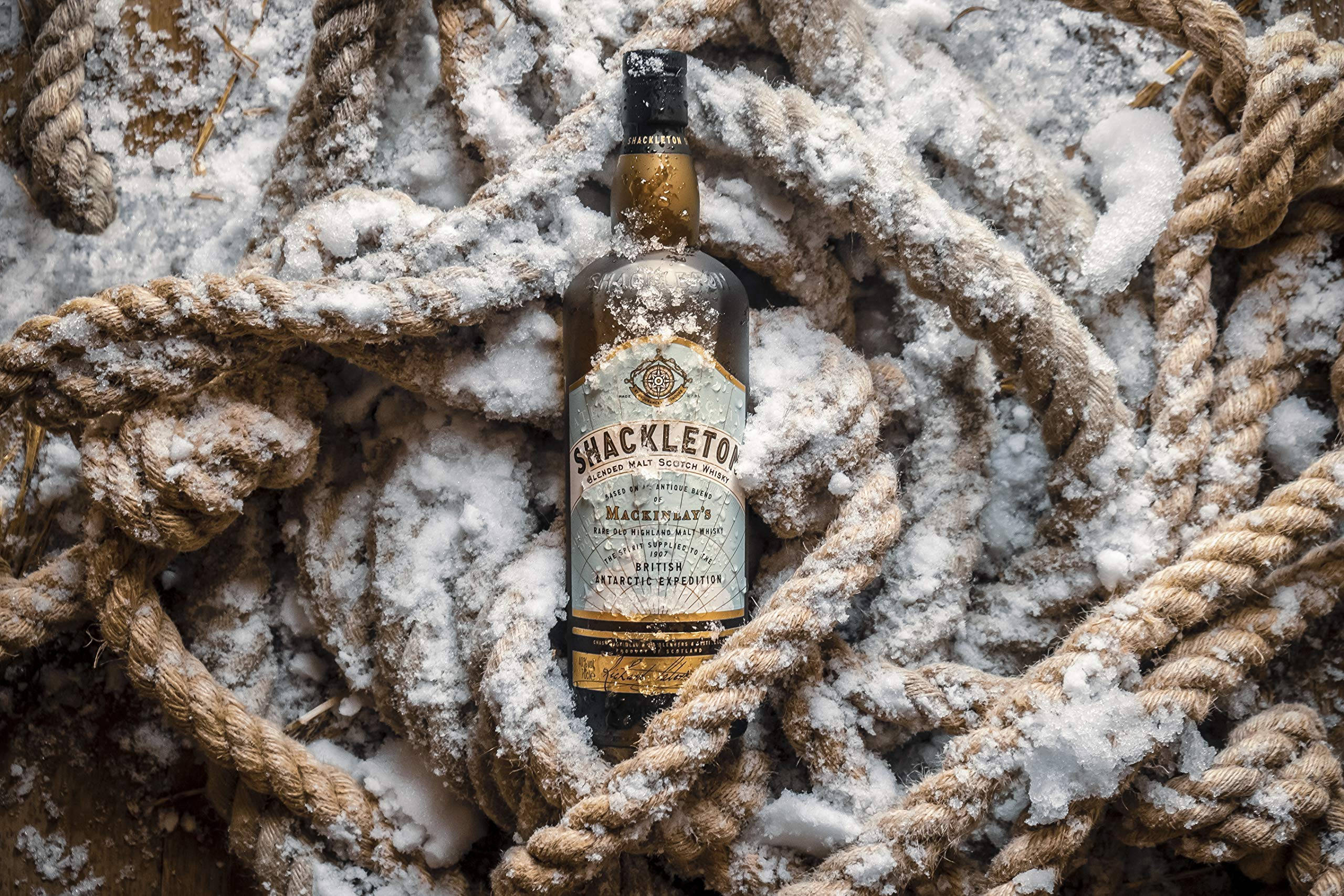 Drink 桌布 壁紙 — 一瓶Shackleton威士忌藏在厚厚積雪的繩索中，喚起艱險的南極探險。