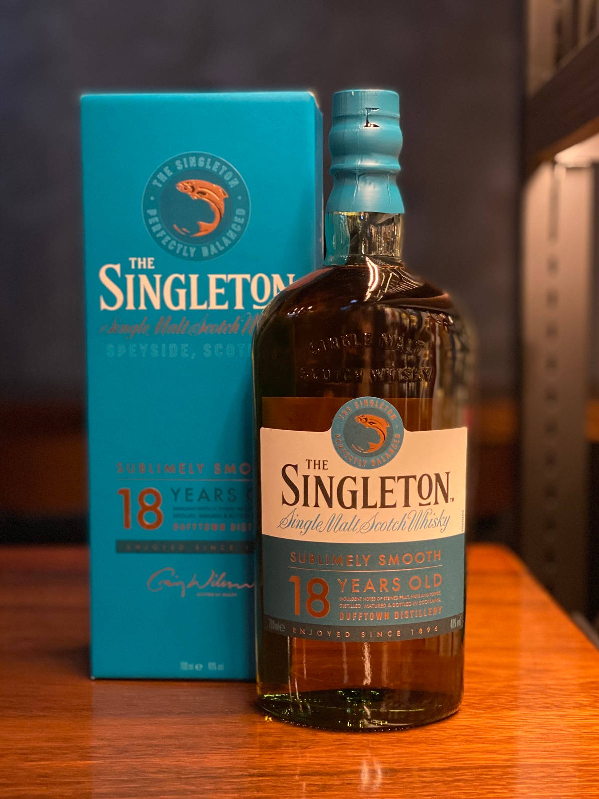 bottle 桌布 壁紙 — 一瓶Singleton 18年單一麥芽蘇格蘭威士忌放在其青綠色盒子旁邊，置於溫暖的木質表面上。