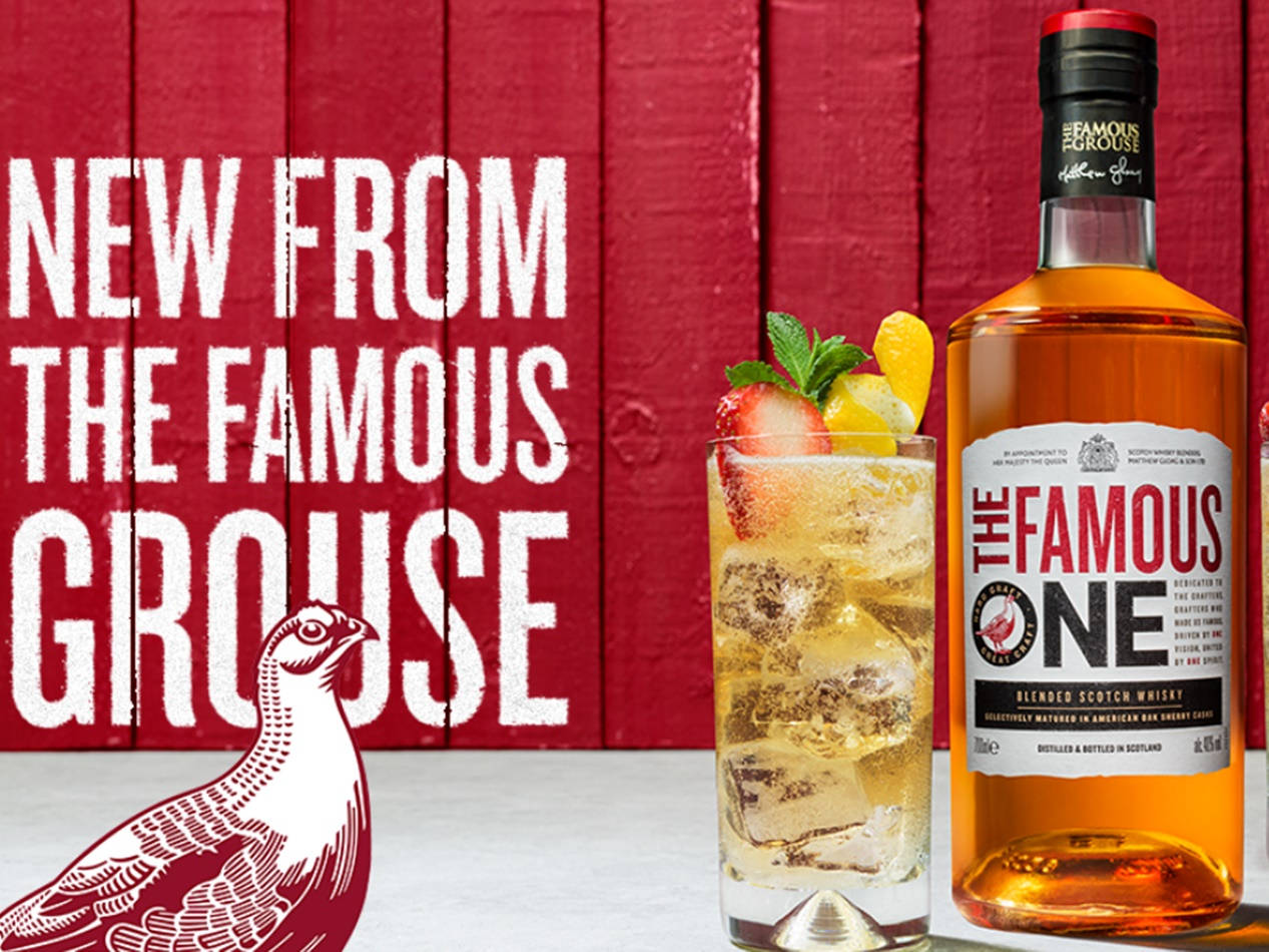 Whiskey 桌布 壁紙 — 一瓶The Famous Grouse One威士忌和一杯裝飾好的雞尾酒放在一面大膽的紅色木牆前，牆上有白色文字和松雞插圖。