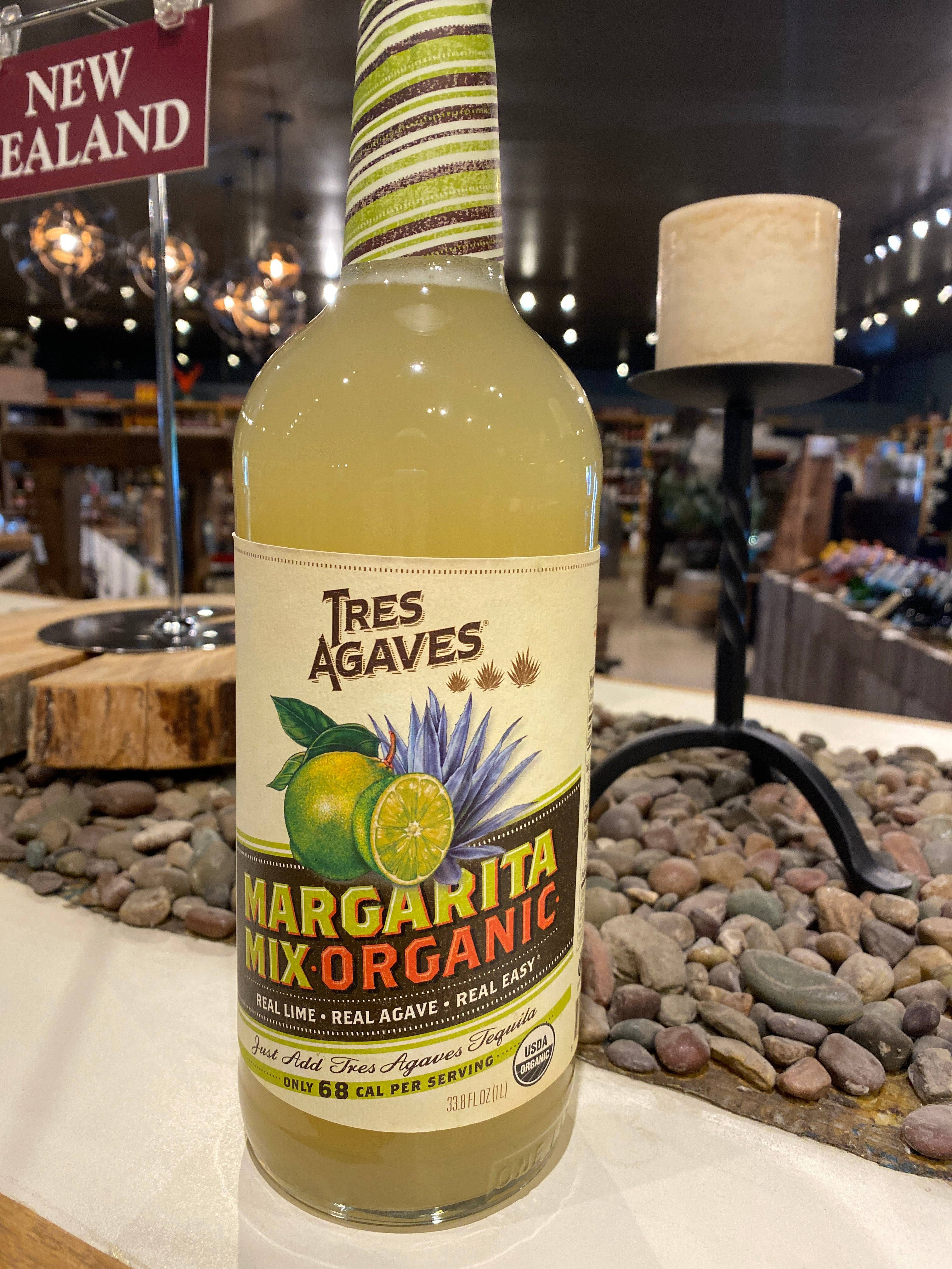 drinks 桌布 壁紙 — 一瓶Tres Agaves有機瑪格麗特調酒混合飲料放在石檯上，店內燈光溫暖，有吊燈和蠟燭。