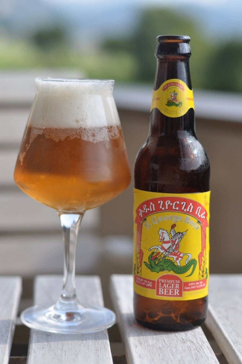Beer 桌布 壁紙 — 一瓶冰涼的 St George 啤酒，帶有泡沫倒出，放在木製露台桌上，旁邊有一個玻璃杯。