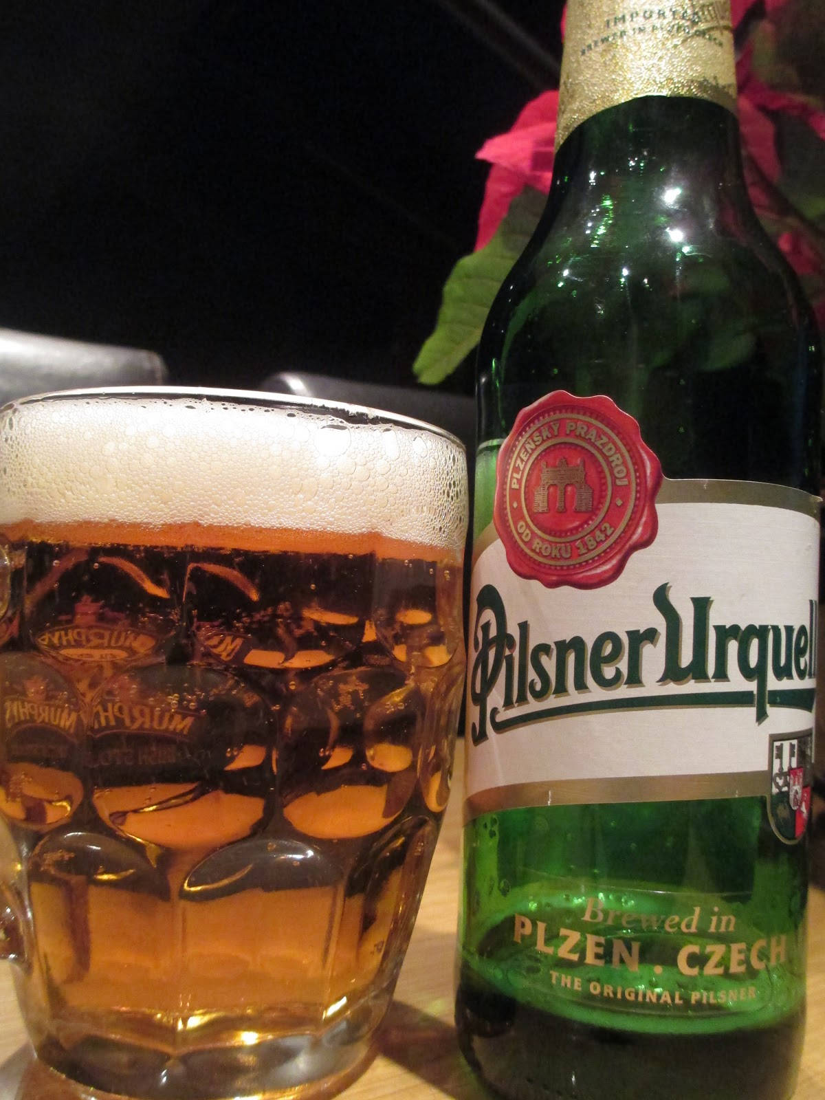 mug 桌布 壁紙 — 一瓶冰涼的Pilsner Urquell啤酒和起泡的玻璃杯放在木桌上，在溫暖的環境光下。