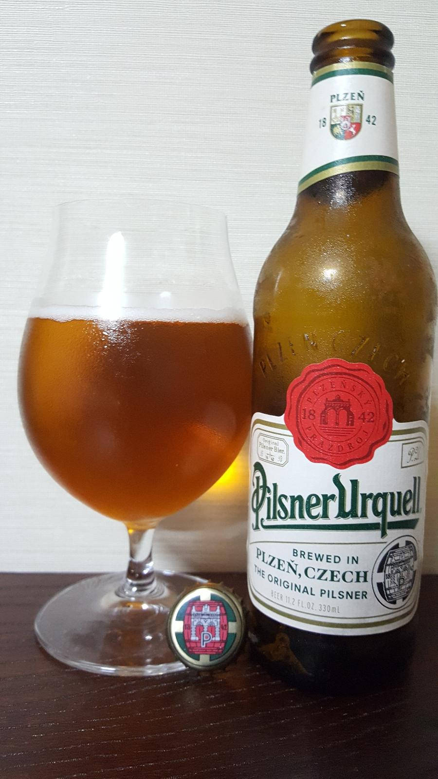 glass 桌布 壁紙 — 一瓶冰涼的Pilsner Urquell啤酒，旁邊放著一個裝滿的玻璃杯，放在深色木桌上。