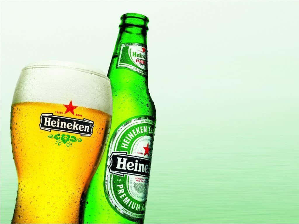 Heineken 桌布 壁紙 — 一瓶冰鎮海尼根啤酒和玻璃杯，在柔和的綠色漸層背景上凝結水珠。