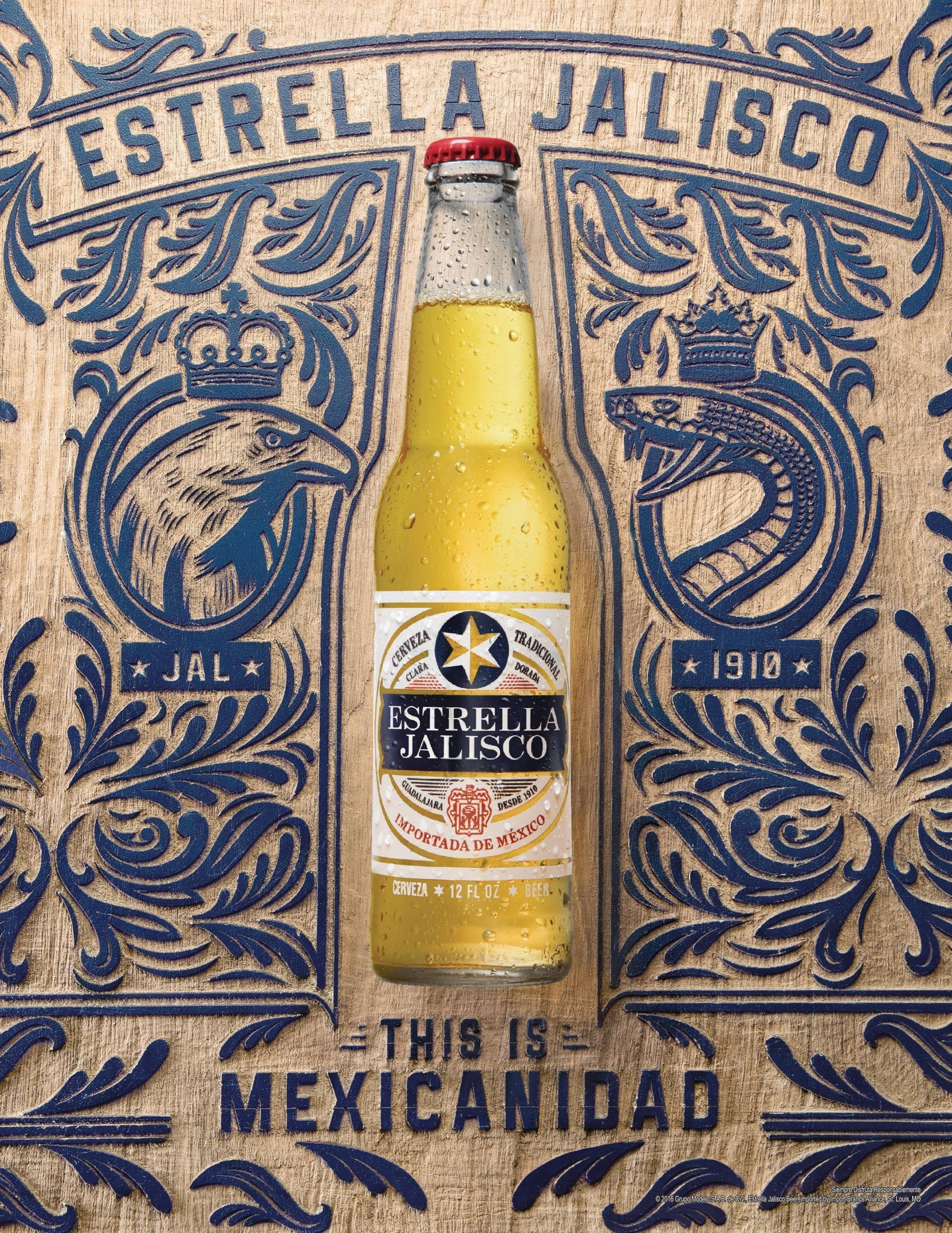 alcohol 桌布 壁紙 — 一瓶冰鎮的Estrella Jalisco啤酒瓶放在一個帶有鷹和蛇圖案的華麗藍色和米色墨西哥民間藝術木板上。