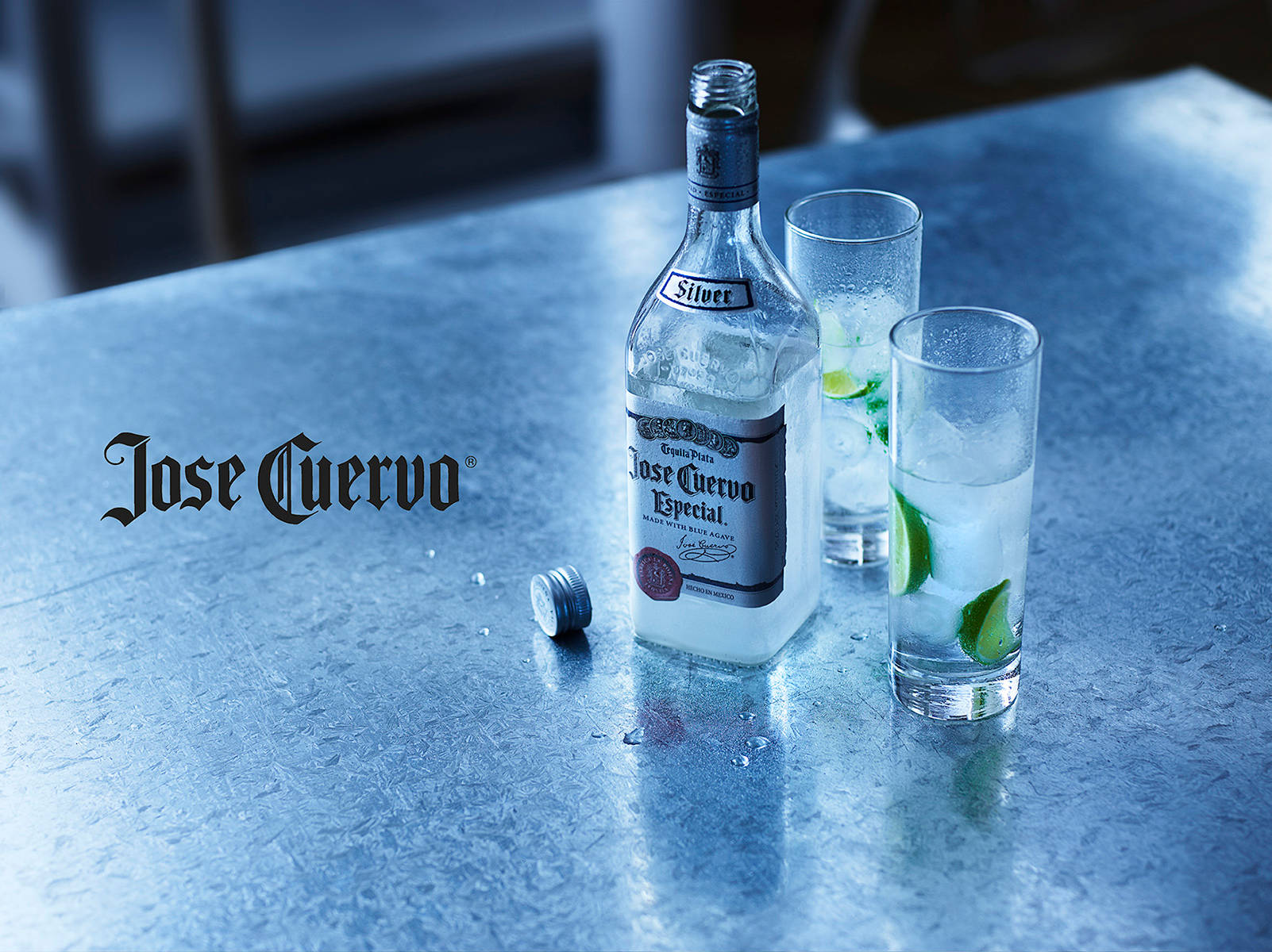 alcohol 桌布 壁紙 — 一瓶冰鎮的Jose Cuervo Silver龍舌蘭酒和兩個帶有萊姆角的玻璃杯放在涼爽的金屬吧檯面上。