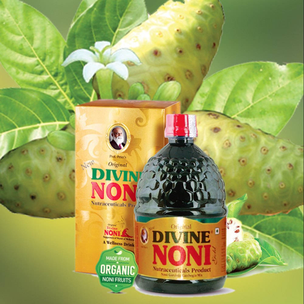 Fruits 桌布 壁紙 — 一瓶及一盒Divine Noni健康飲品，周圍環繞著新鮮的綠色諾麗果和葉子，並有白色花朵。