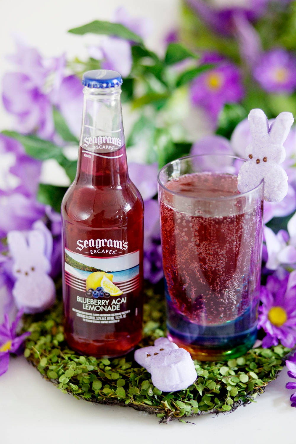 Seagram's Blueberry Acai Lemonade 瓶子和杯子，搭配兔子糖果和紫色花朵。 — Juice Wrld 壁紙
