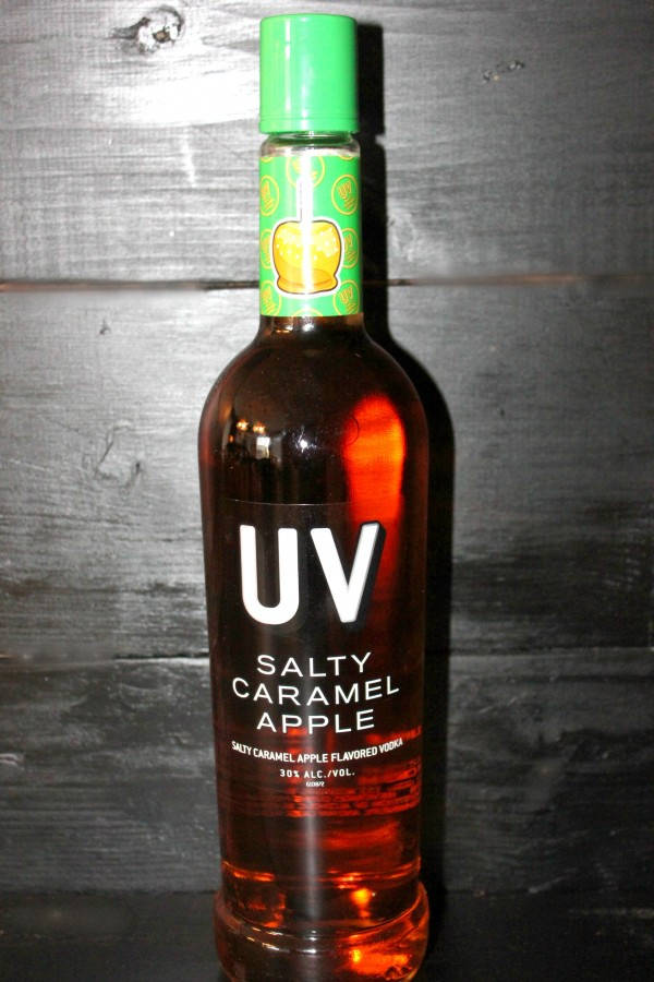 紅色動圖 桌布 壁紙 — 一瓶帶有綠色蓋子的UV Salty Caramel Apple伏特加酒，立在深色木質背景前。