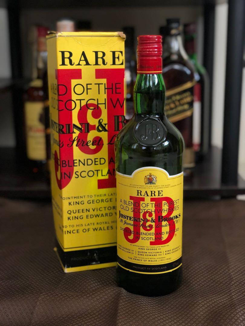 drinks 桌布 壁紙 — 一瓶復古J&B Rare蘇格蘭威士忌，連同原裝黃色盒子，放置在紋理表面上，展示大膽的紅色和黑色字體。