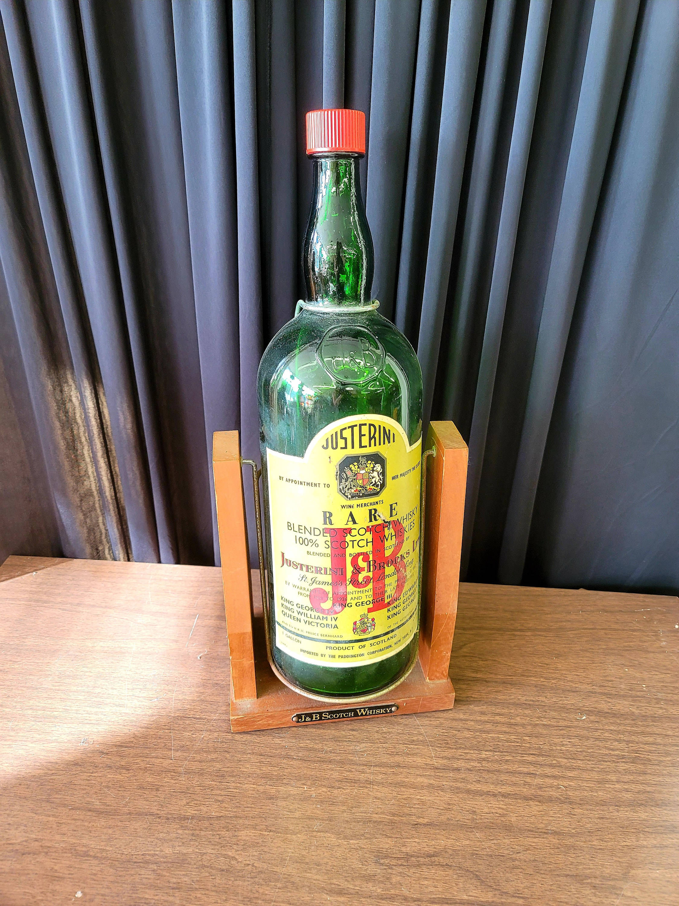 drinks 桌布 壁紙 — 一瓶復古綠色Justerini & Brooks稀有調和蘇格蘭威士忌，放在木架上，置於木桌上，背景是深色窗簾。