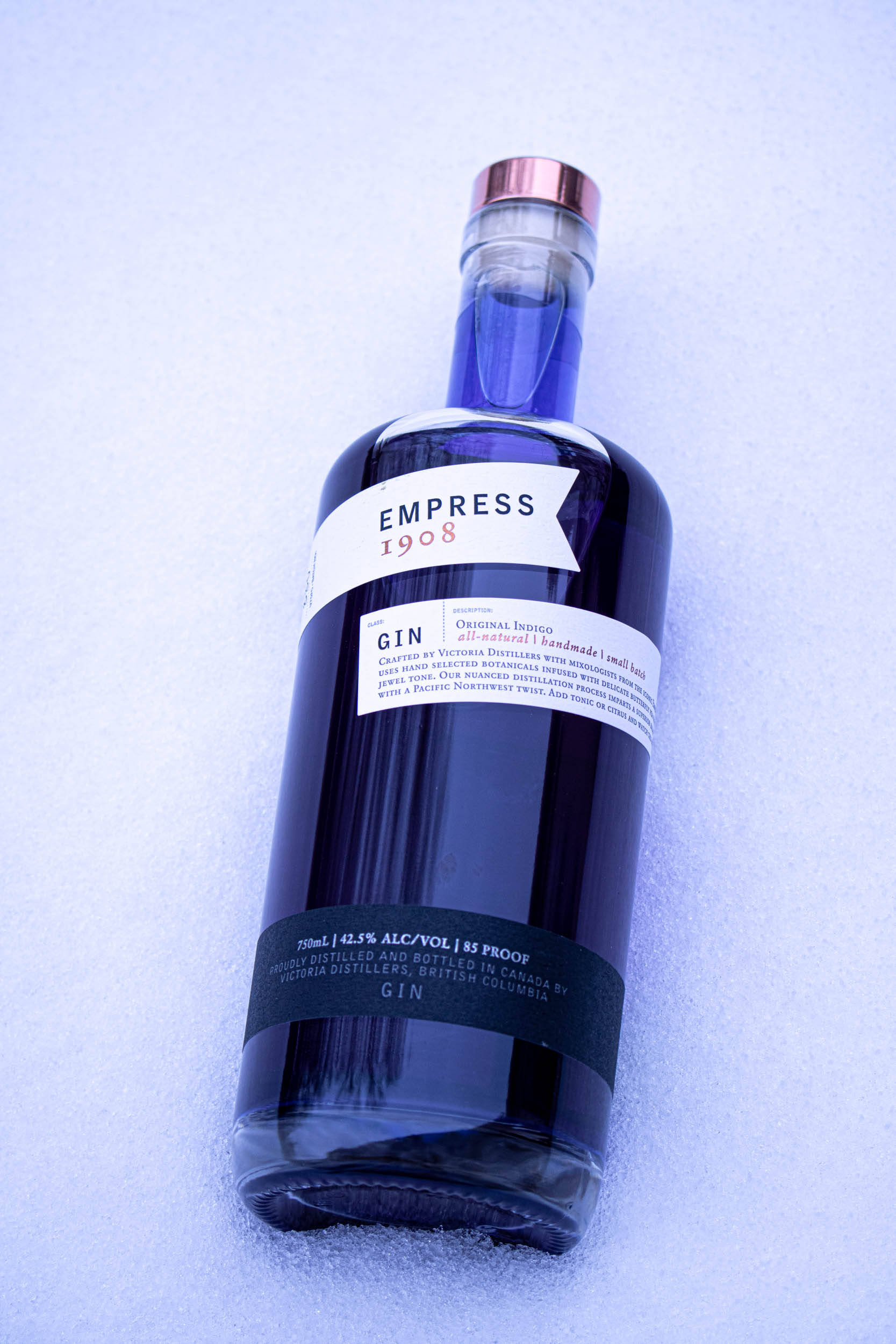 bottle 桌布 壁紙 — 一瓶標有Empress 1908的時尚深藍色琴酒瓶，在冷藍光下放置在雪地上。