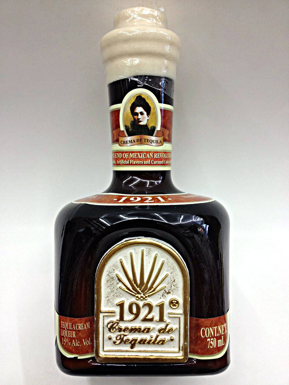 drinks 桌布 壁紙 — 一瓶深色玻璃瓶裝1921 Crema de Tequila，帶有復古標籤和肖像，背景為純白色。