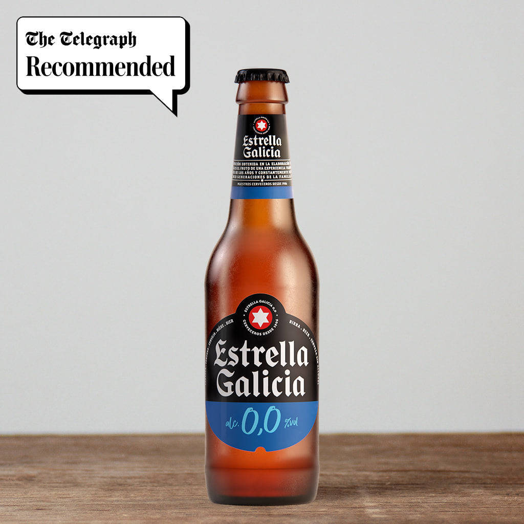 alcohol 桌布 壁紙 — 一瓶清澈琥珀色的Estrella Galicia 0.0無酒精啤酒立在木質表面上，上方有「The Telegraph Recommended」對話框。