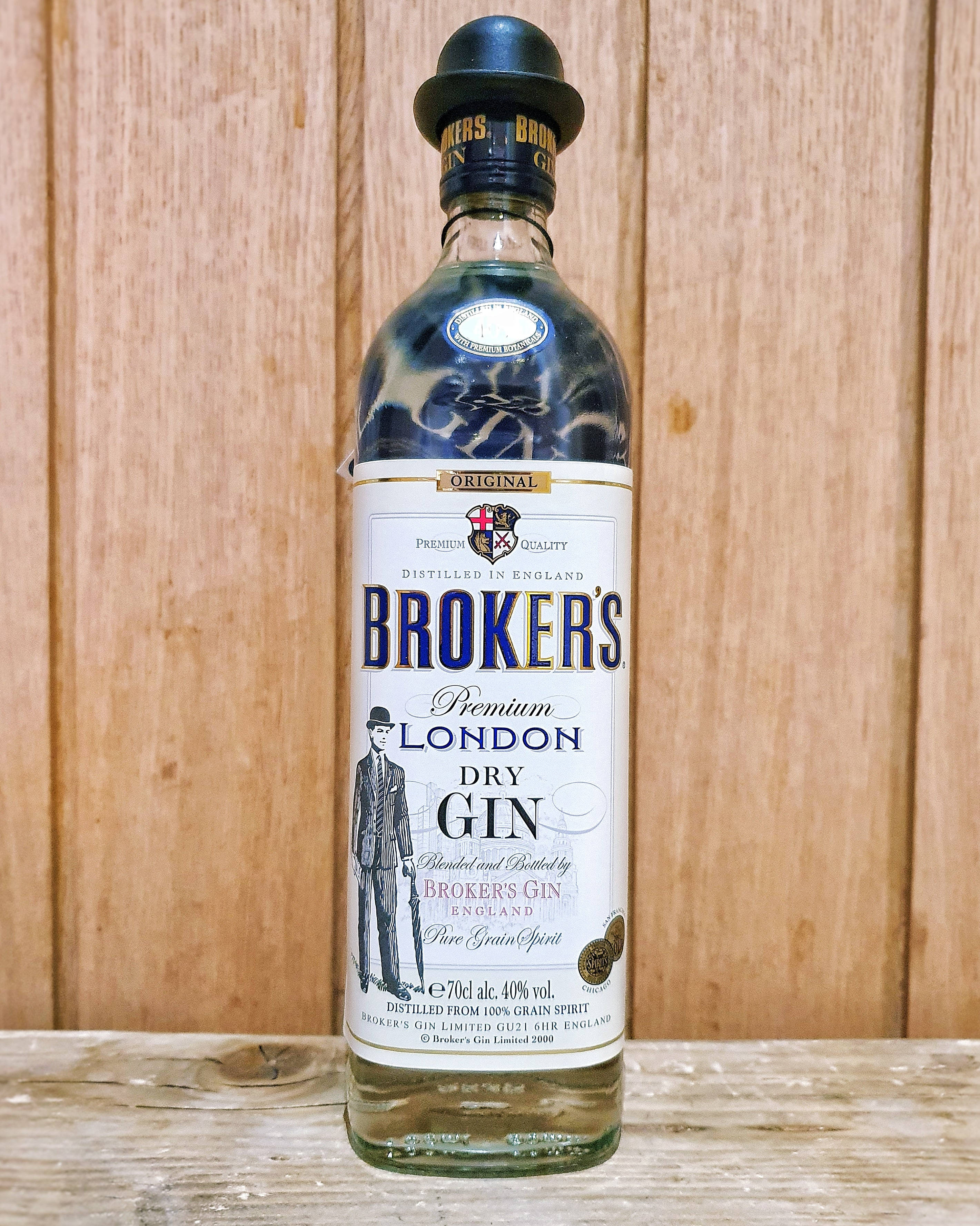 bottle 桌布 壁紙 — 一瓶清澈的 Broker's Premium London Dry Gin 直立放在風化的木質表面上，背景是相配的木質背景。