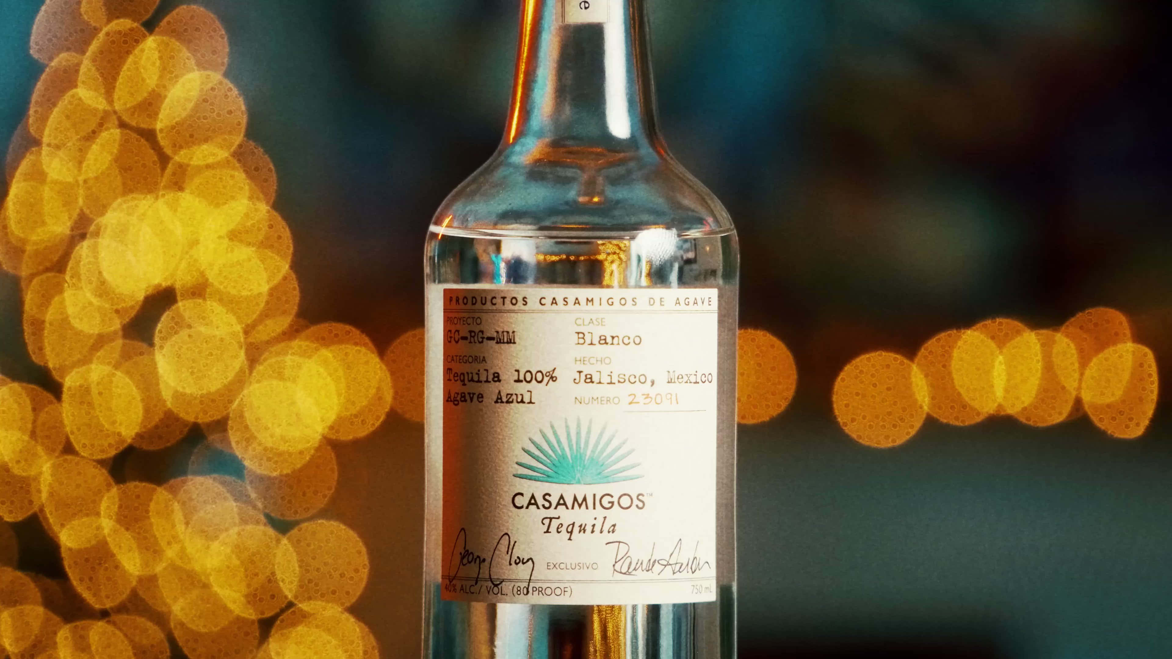 bottle 桌布 壁紙 — 一瓶清澈的Casamigos Blanco龍舌蘭酒，置於溫暖金色散景燈光的背景中央。