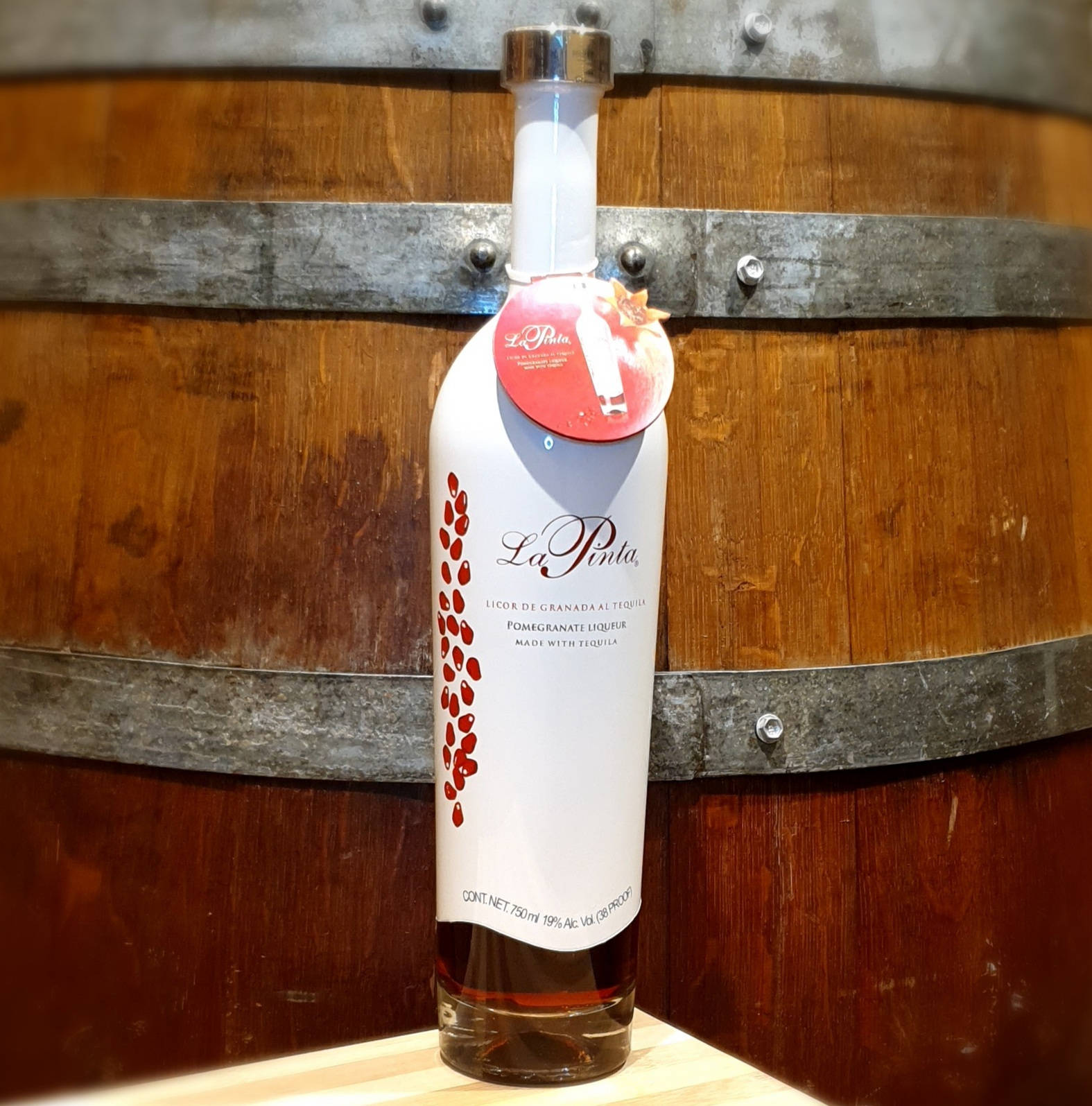 Drink 桌布 壁紙 — 一瓶白色La Pinta石榴利口酒放在木質表面上，背景是質樸的葡萄酒桶。