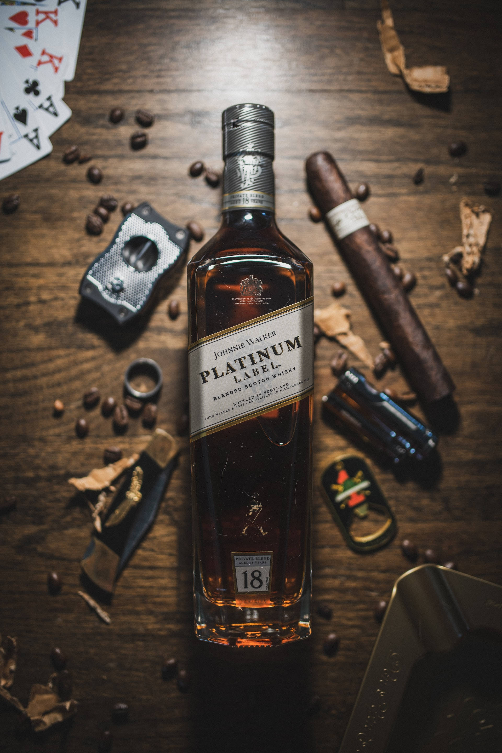 cigar 桌布 壁紙 — 一瓶約翰走路鉑金標籤威士忌放在鄉村風格的木桌中央，周圍環繞著雪茄、撲克牌和咖啡豆。