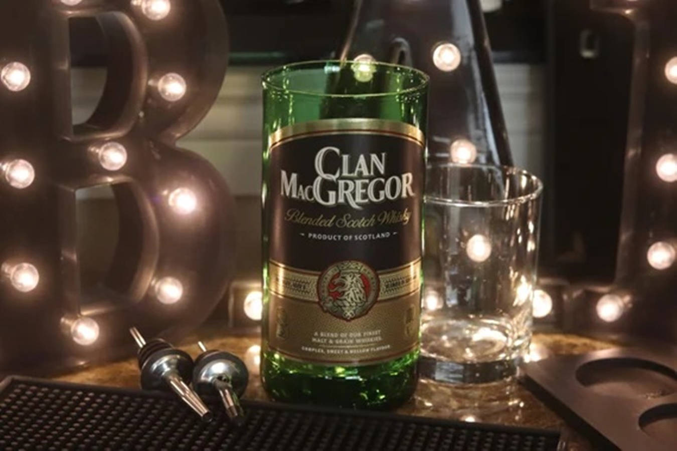 Whiskey 桌布 壁紙 — 一瓶綠色Clan MacGregor威士忌放在酒吧上，旁邊有發光的招牌燈和一個玻璃杯。